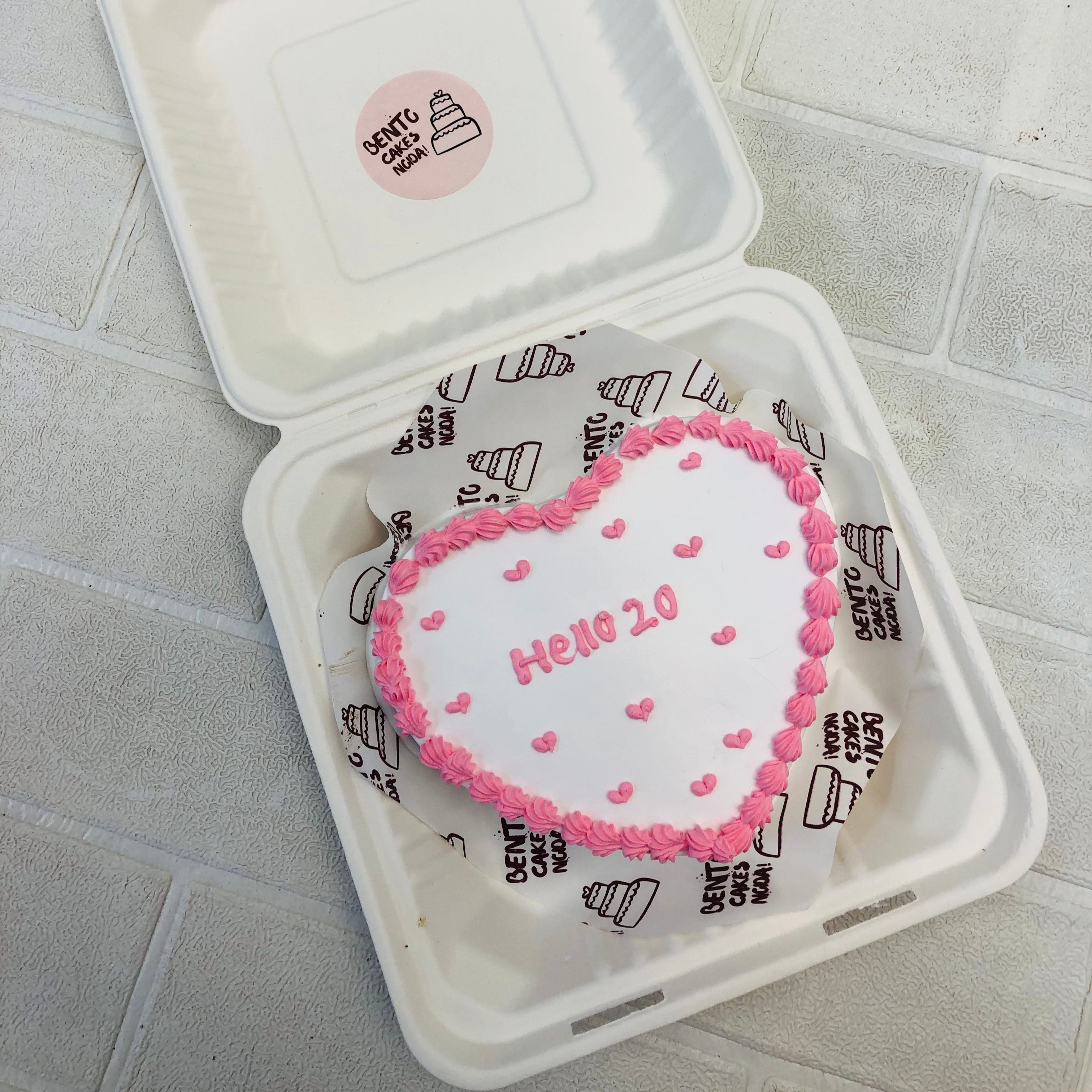 A white heart bento cake with light pink boundary design and full of little hearts design on it.