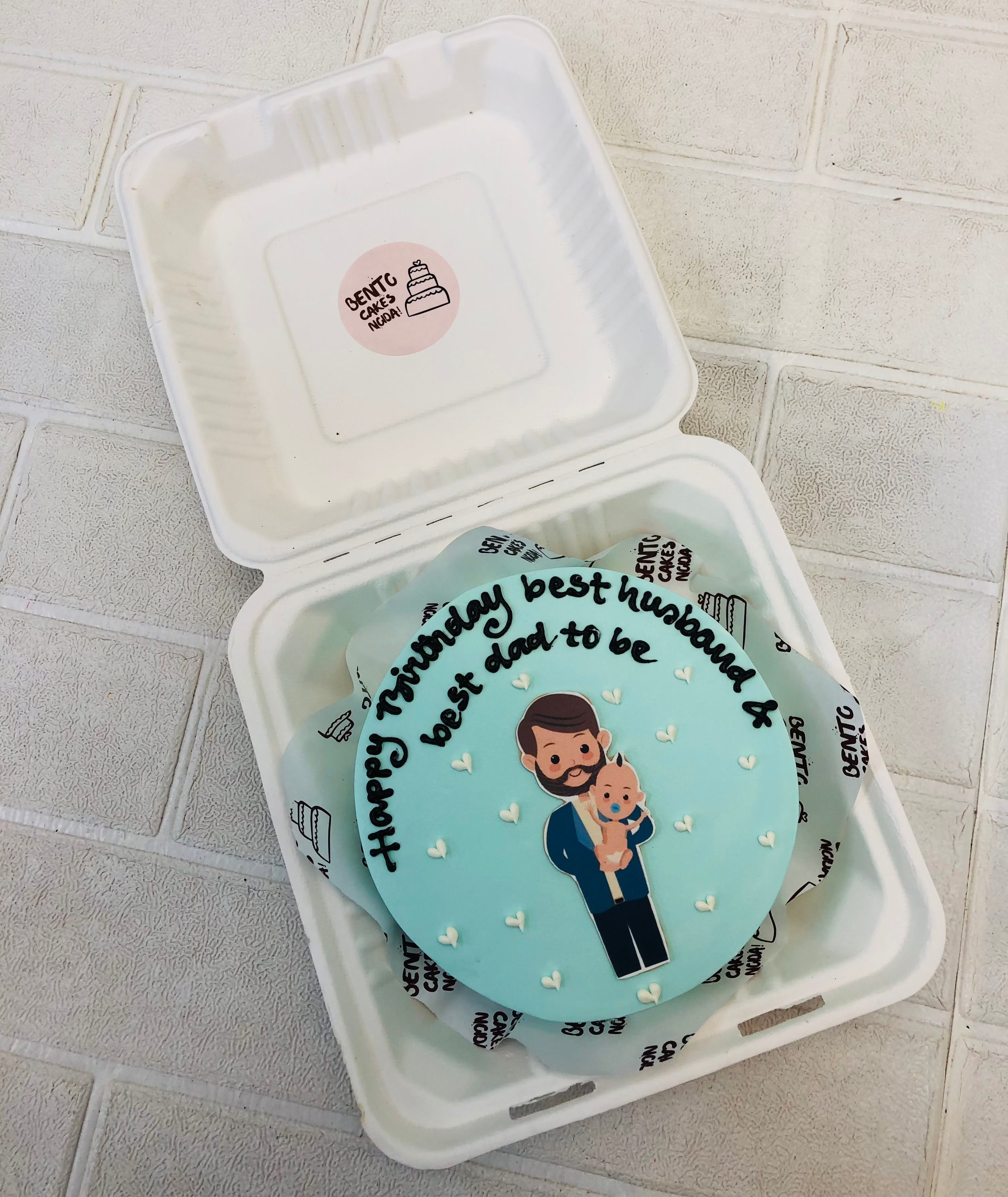 A cool blue bento cake designed for husband and dads birthday with a sticker and decorated with little white hearts.