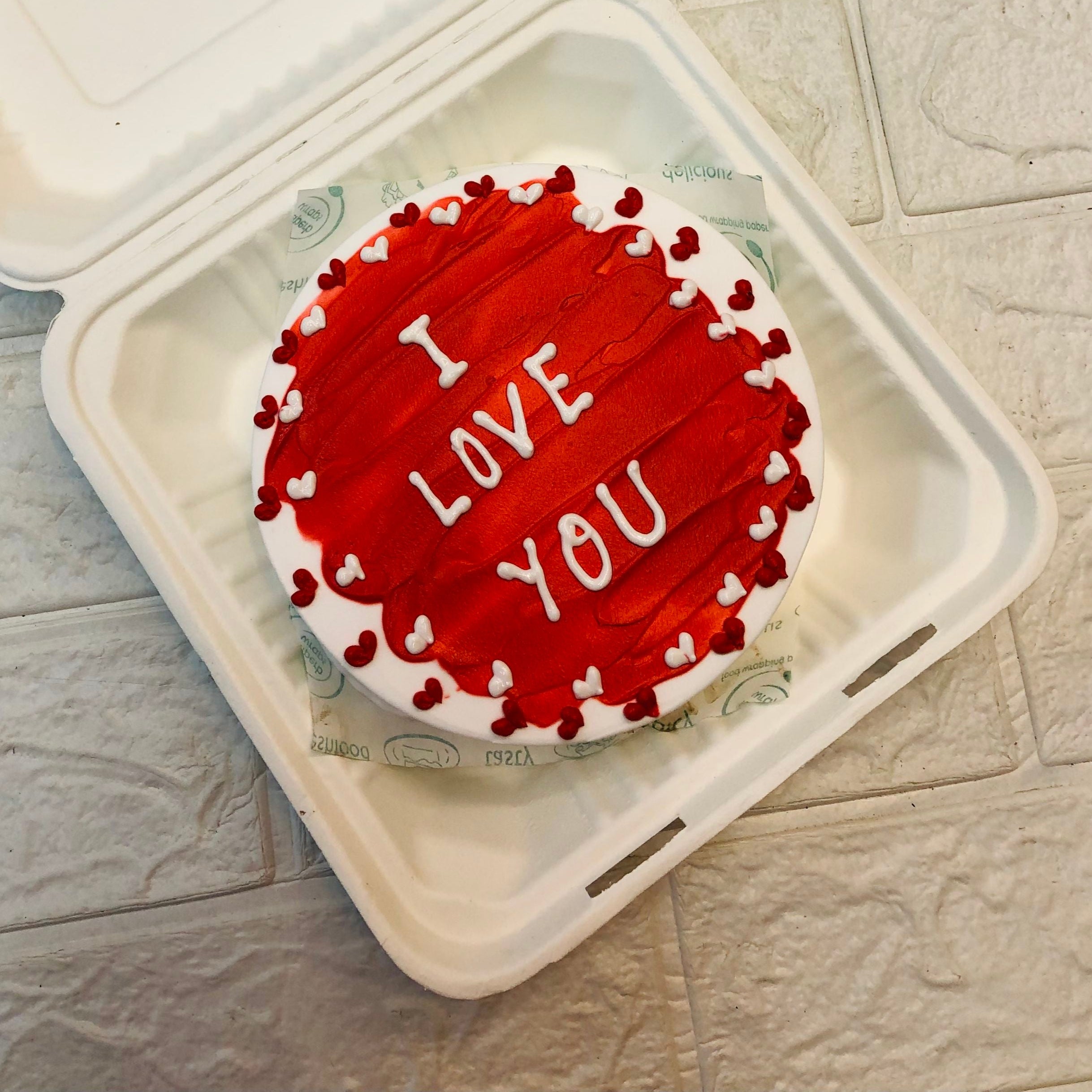 I love you theme white bento cake is beautifully designed and surrounded by red and white heart designs.