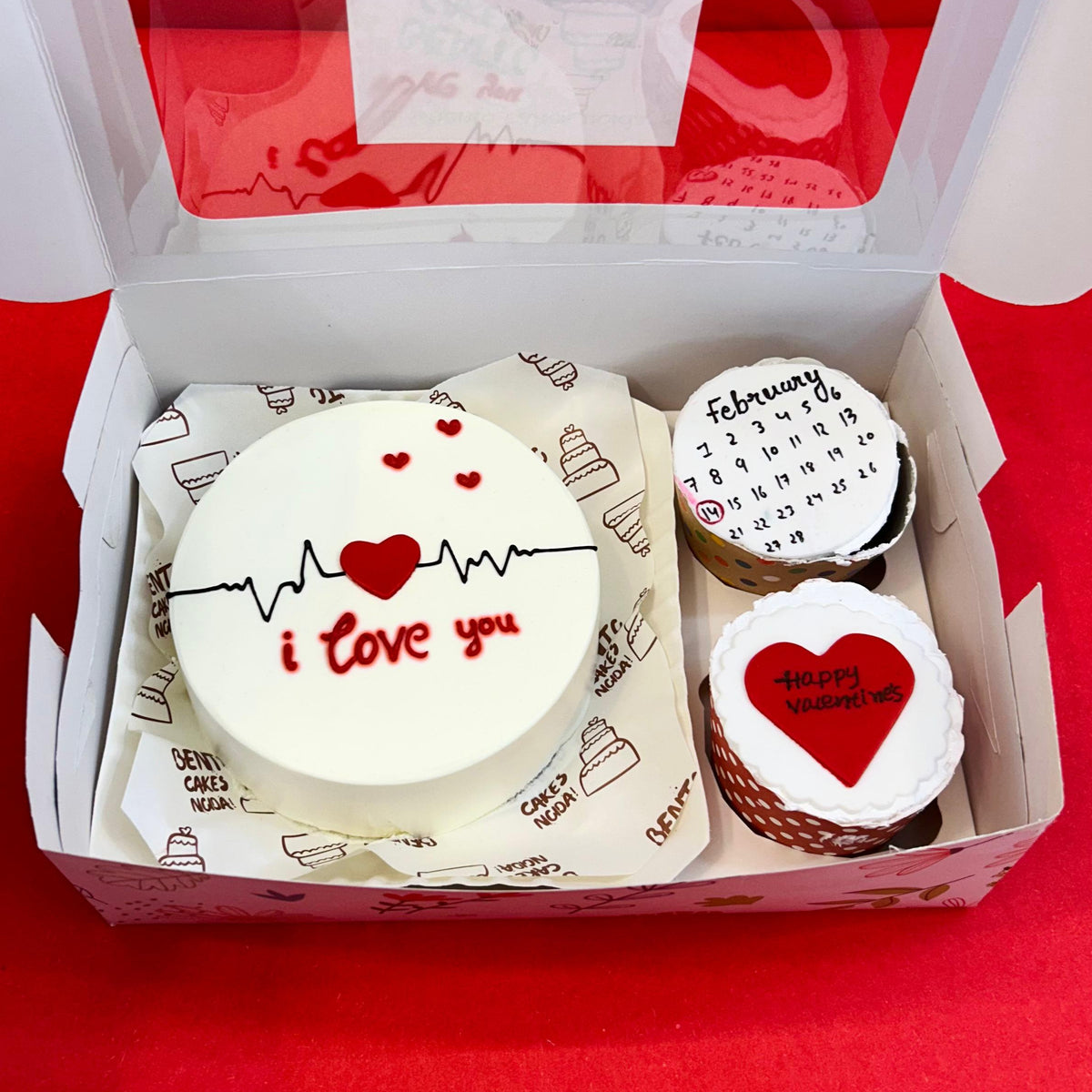 A charming display of cupcakes alongside a heart-shaped cake, including a mini bento combo cake that says "I love you."