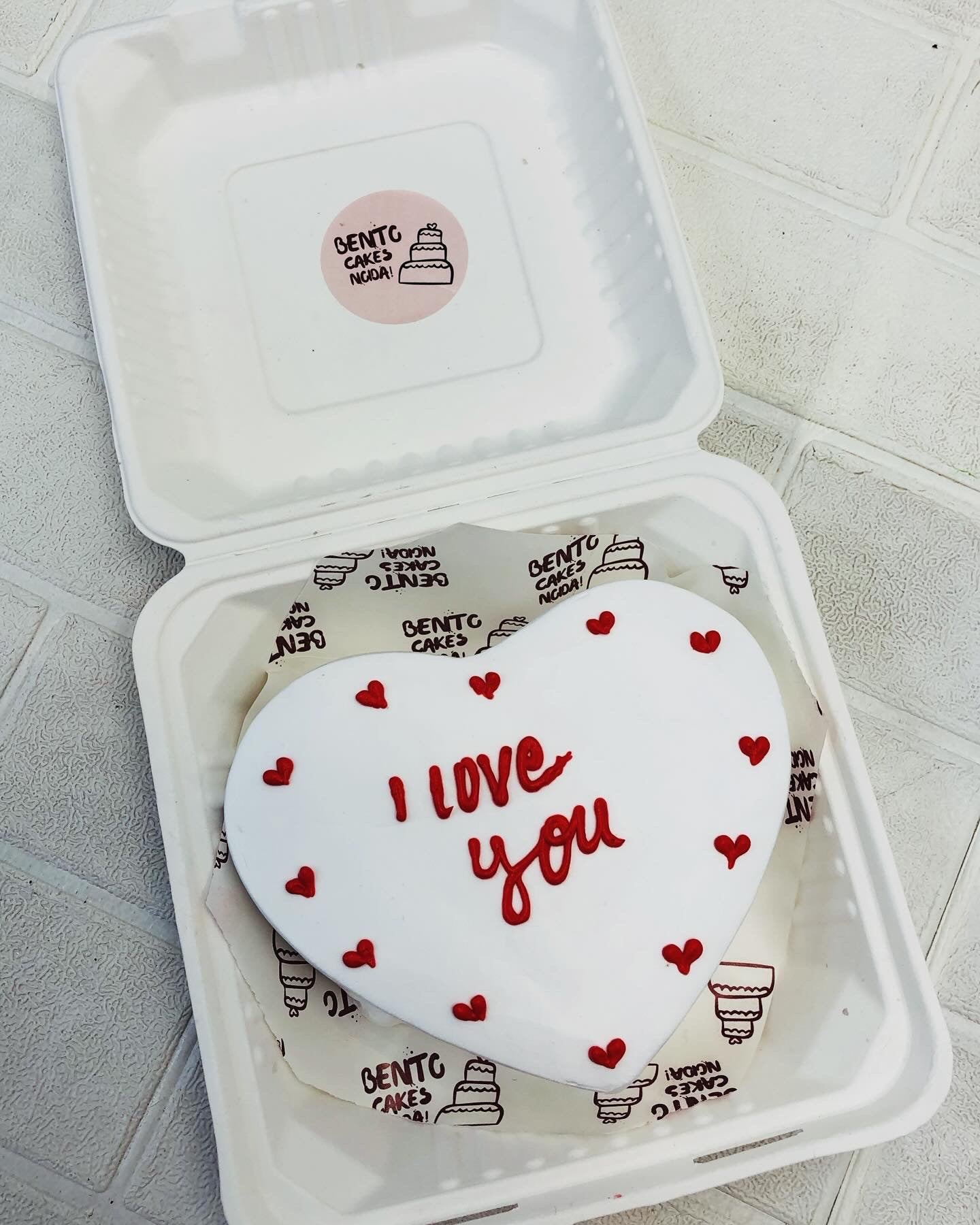 A white heart shape cake with red hearts design and "i love you" text.