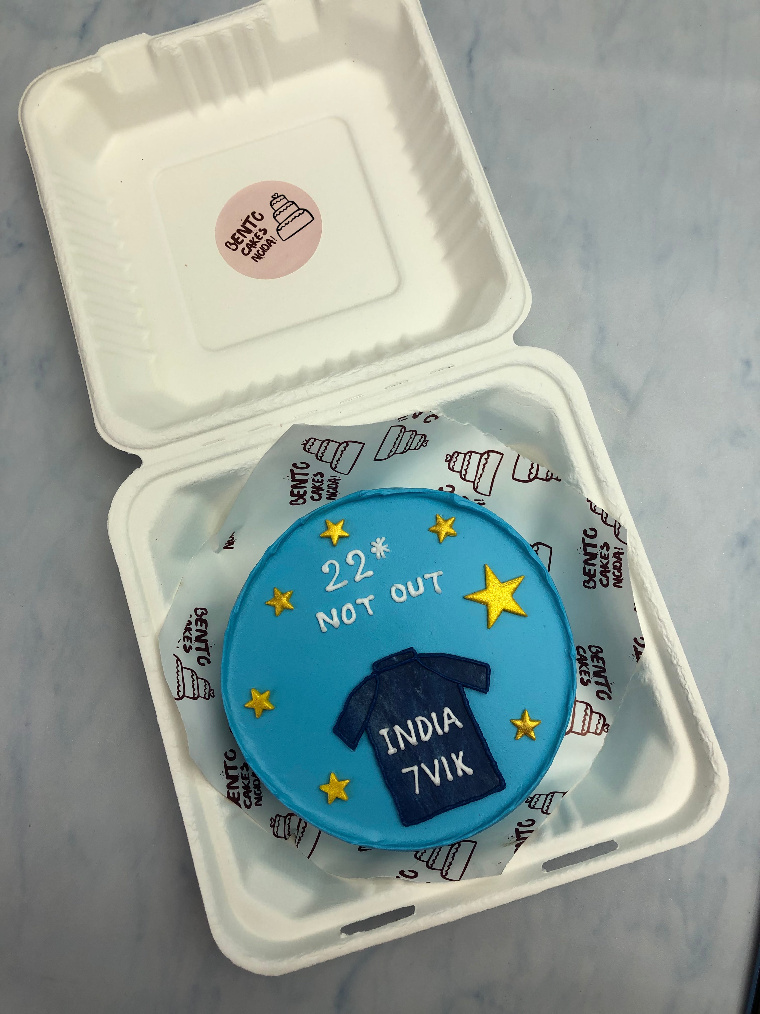 A sky blue bento cake with indian cricket Tshirt and fillwed with golden stars.