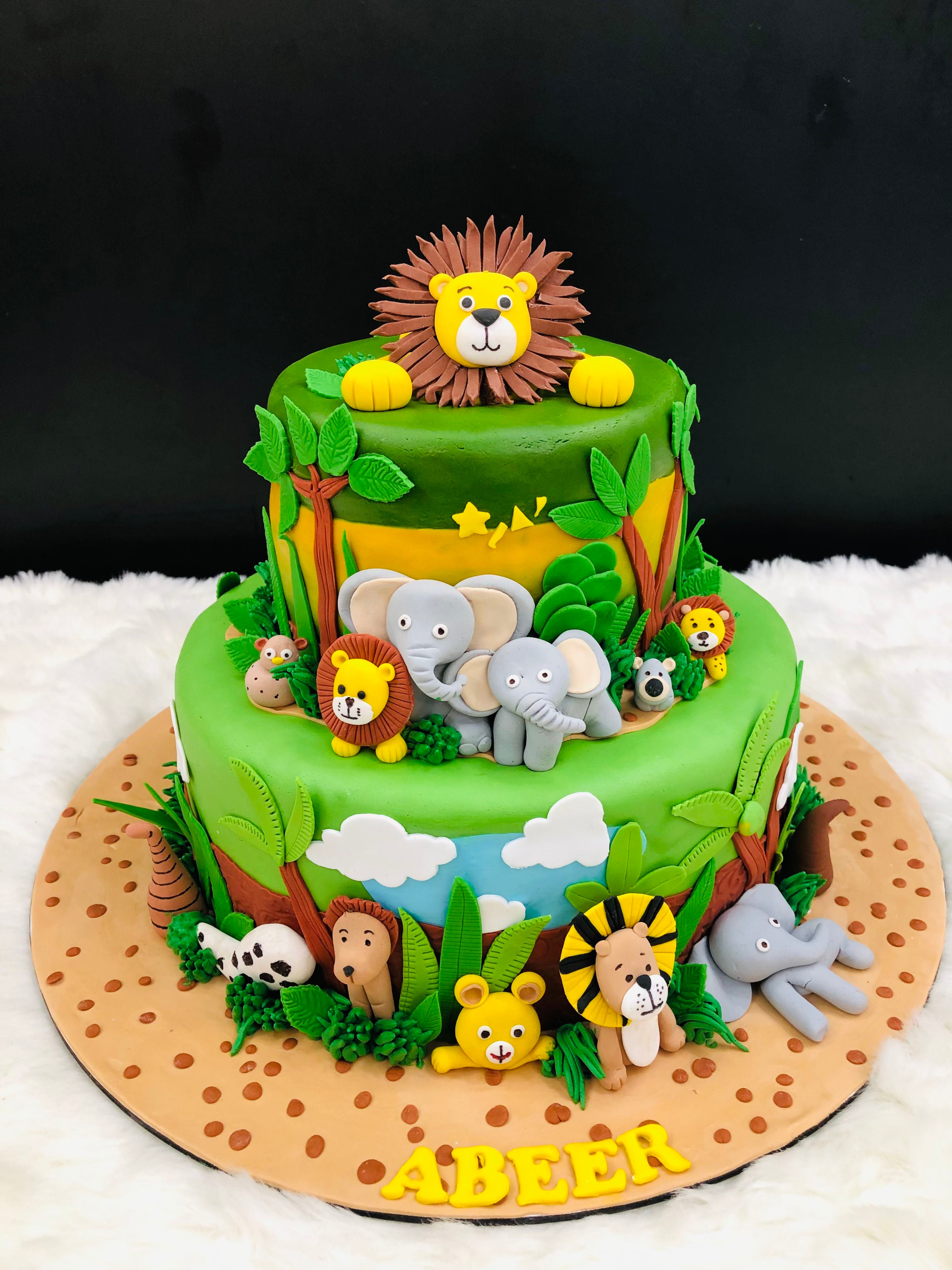 A colorful cake adorned with various jungle animals, featuring a prominent lion on top, perfect for a themed celebration.