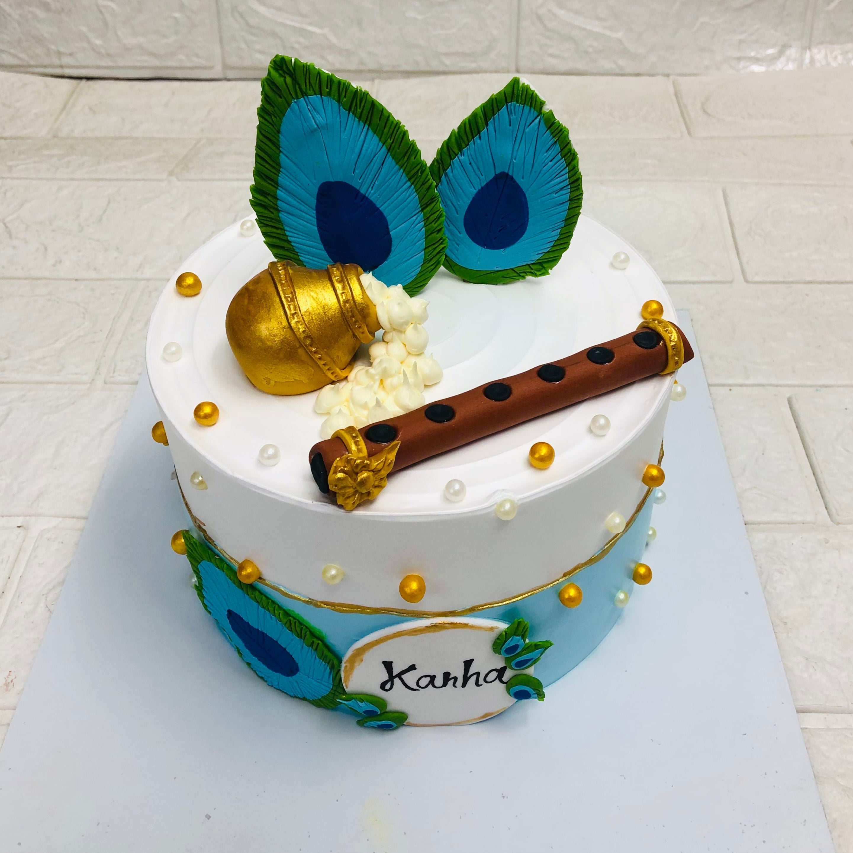 A beautifully decorated cake featuring vibrant peacock feathers and an elegant flute, showcasing exquisite artistry.