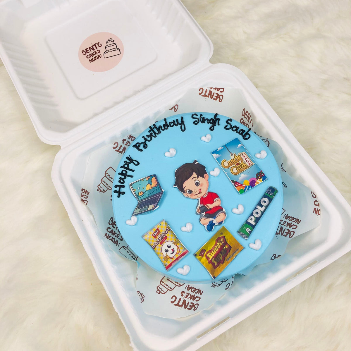 A beautifully decorated birthday cake inside a bento box, emphasizing its colorful icing and celebratory theme.
