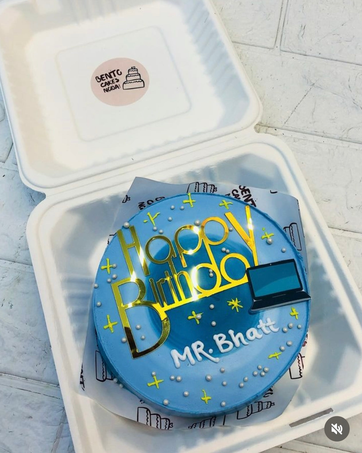 A aesthetic blue bento cake having a laptop print, and decorated with golden stars theme for birthday.