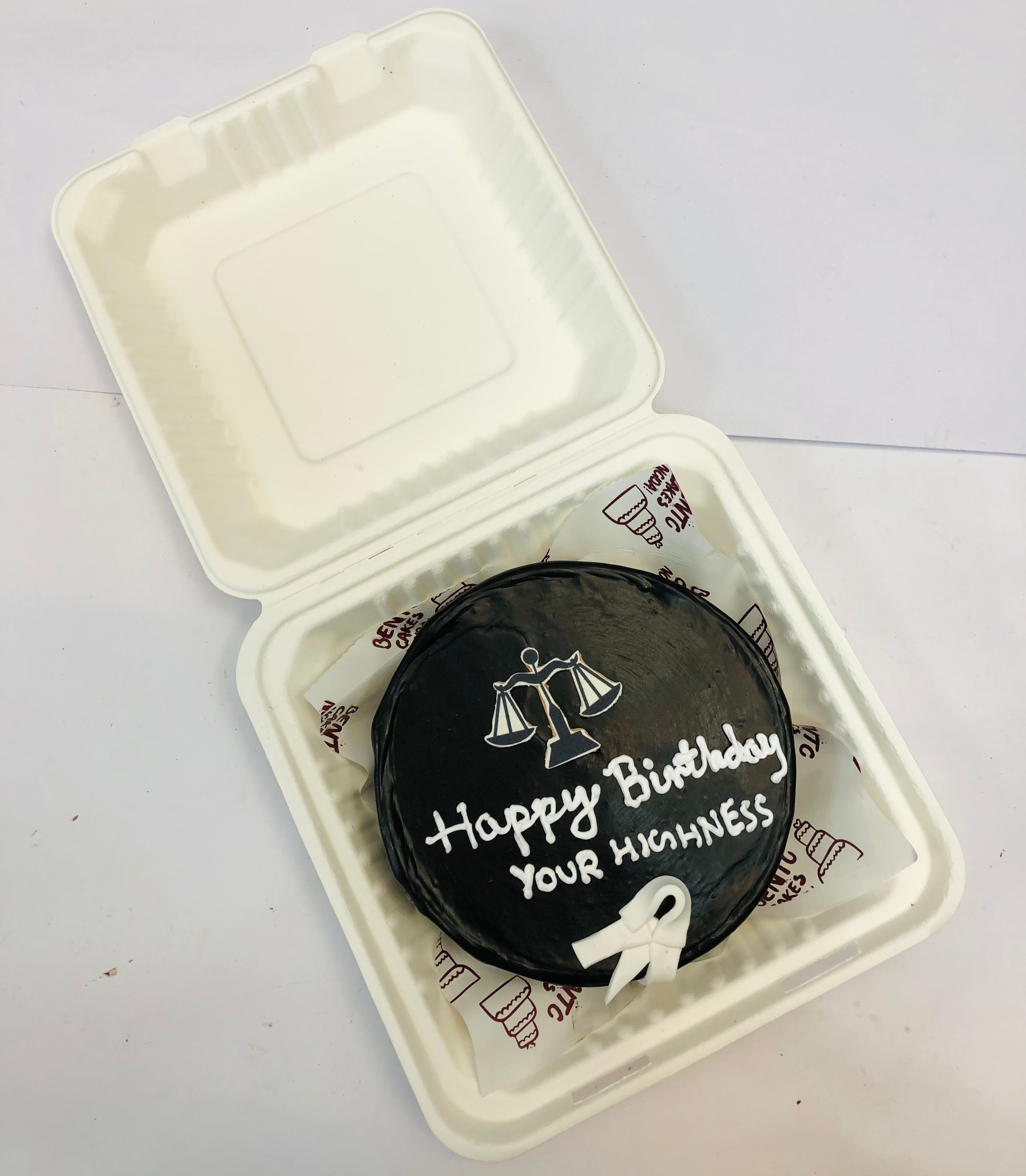 A chocolate black bento cake is designed for a lawyers birthday with law theme stickers.
