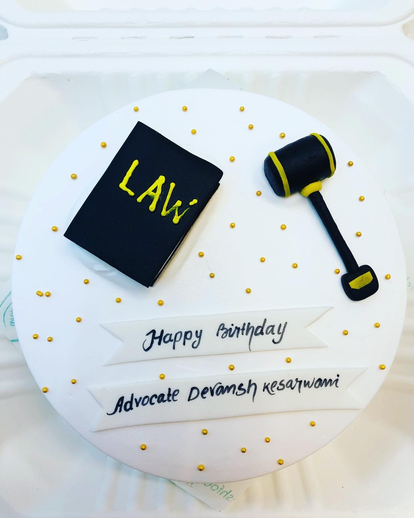 A white  is decorated on a law theme, a book and a hammer with black fondant beautifully placed on it.