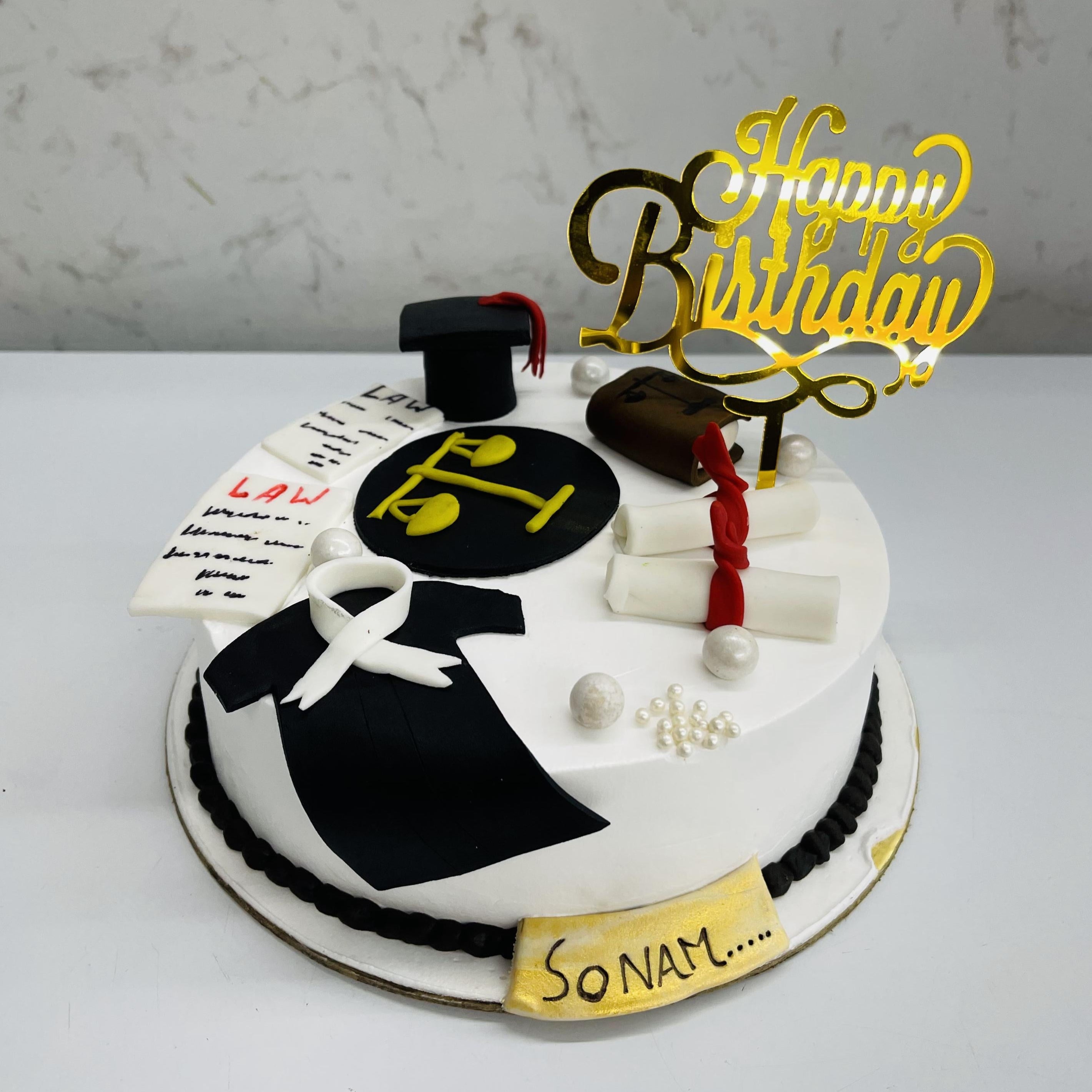 A birthday cake featuring a black and white design, adorned with law-themed decorations, symbolizing a legal celebration.
