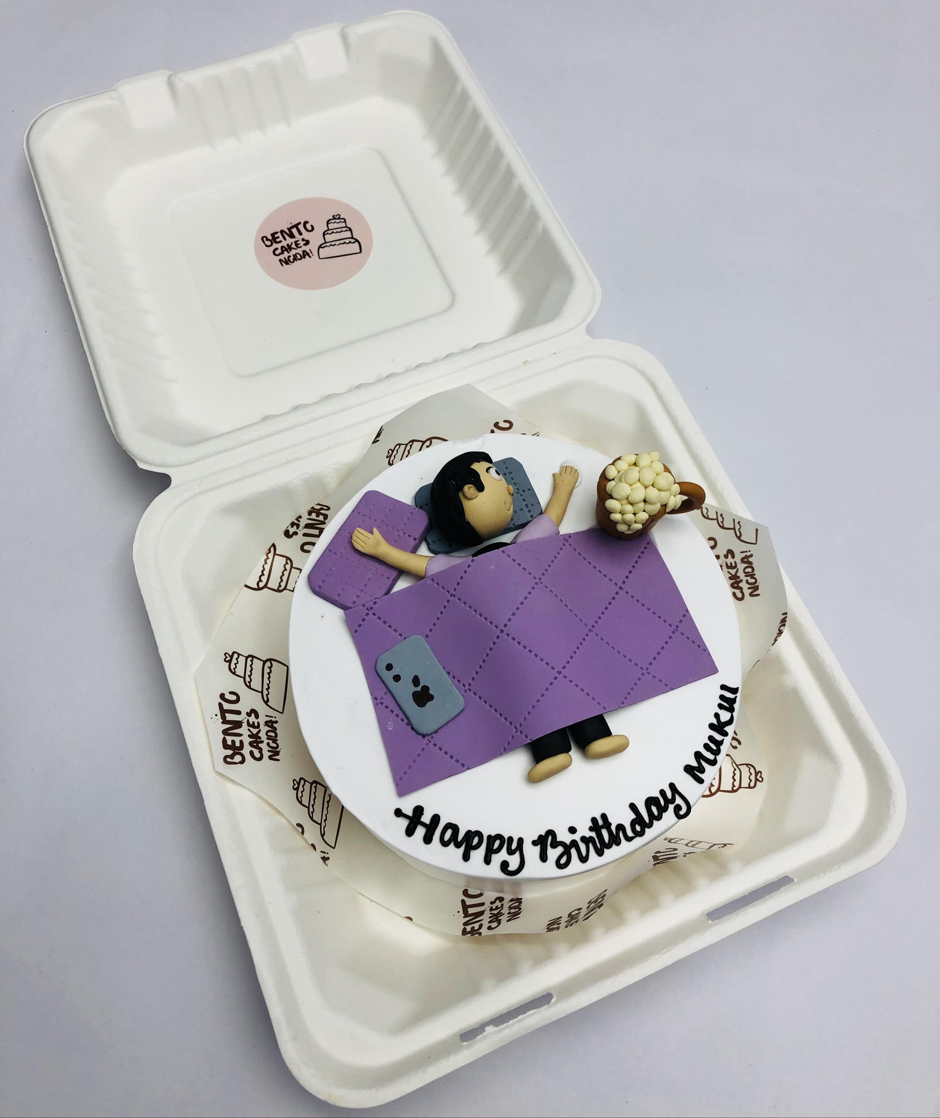 A white bento cake having lazy men sleeping, eating and enjoying his birthday.