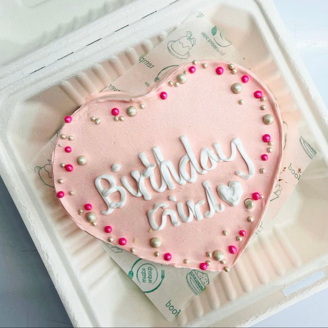 A heart-shaped cake adorned with pink white sprinkles, symbolizing love and celebration.