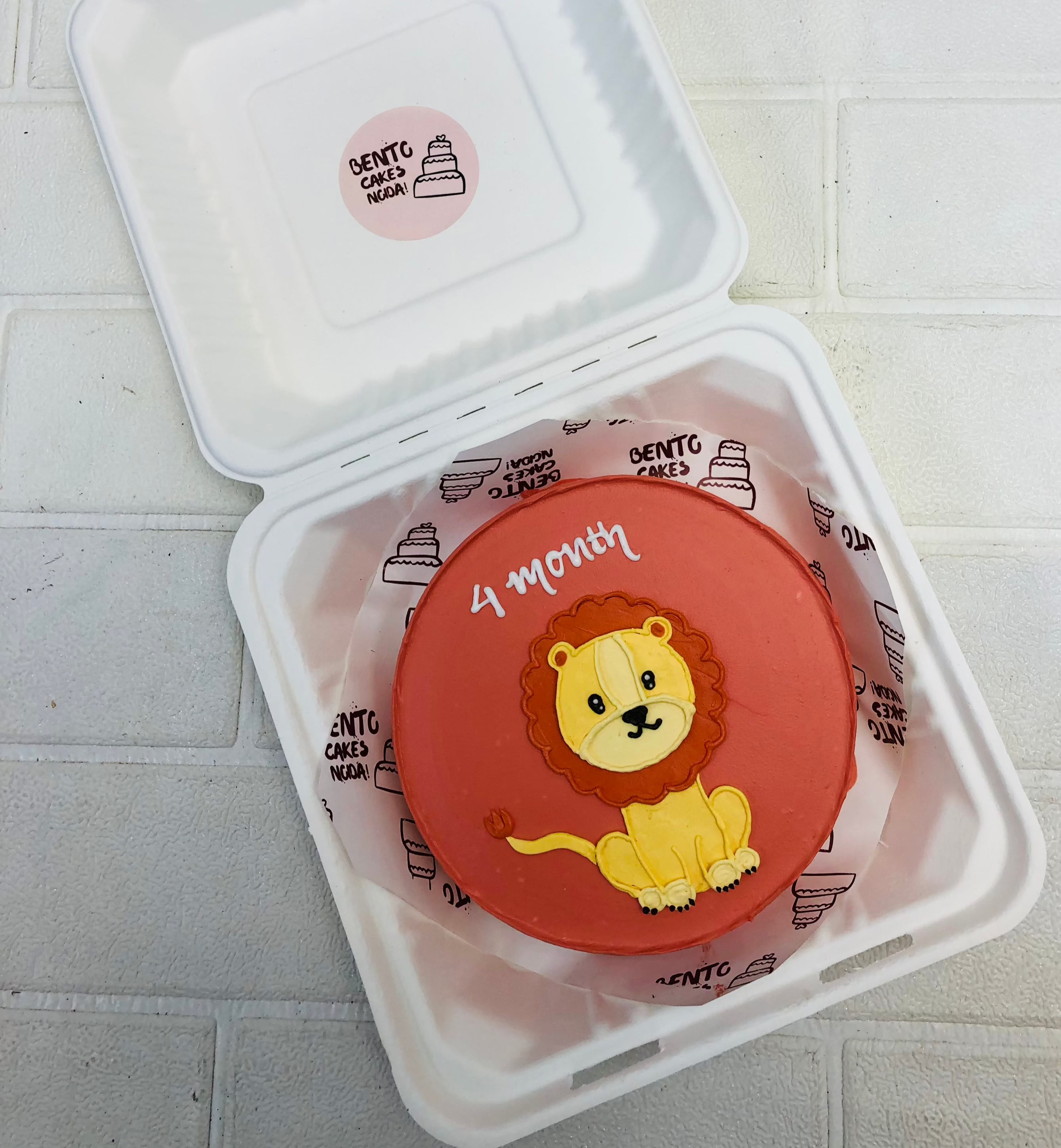 A dark red bento cake with cute lion drawing.