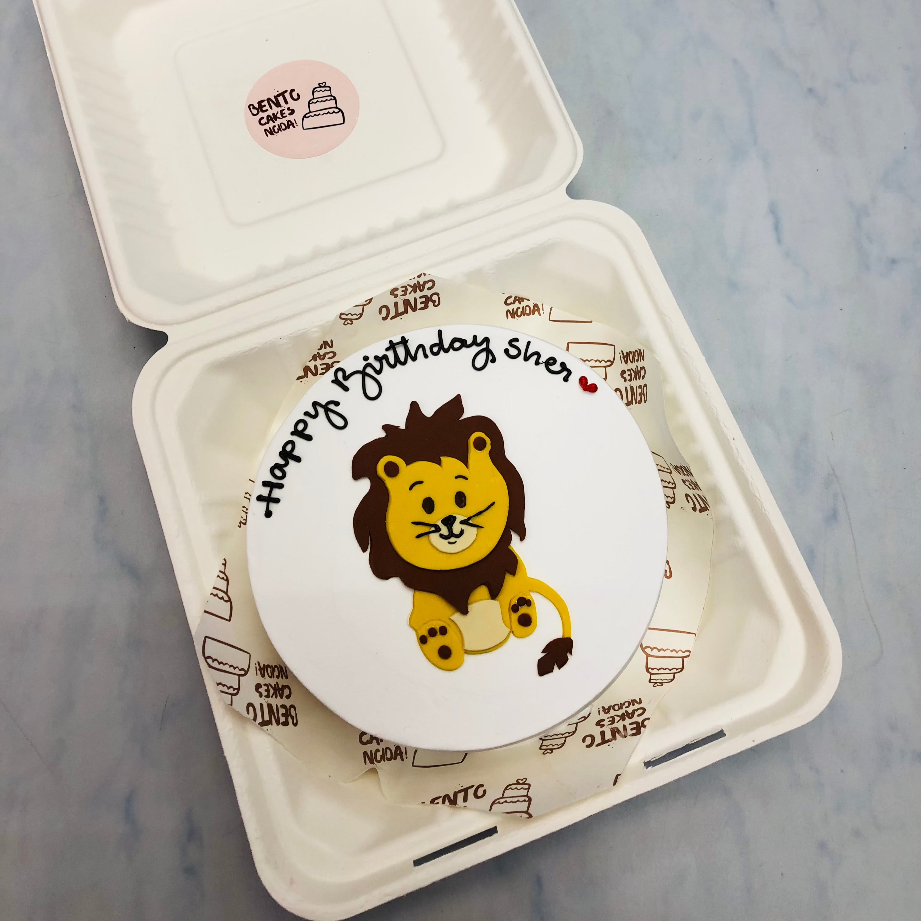 A white cake with a fondant lion design with a happy b'day text.