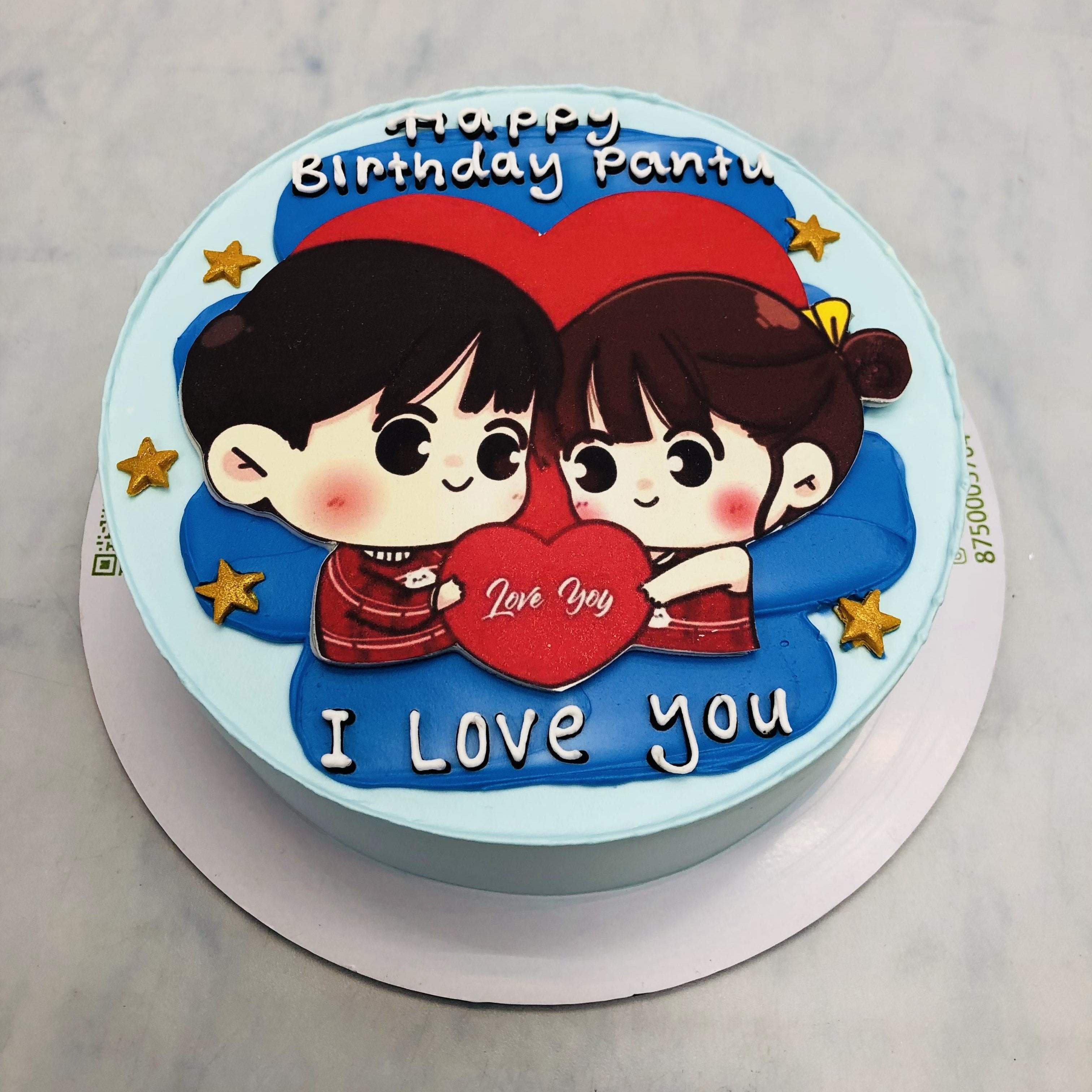 A light blue cake decorated with blue shades and a couple sticked on it with golden stars.