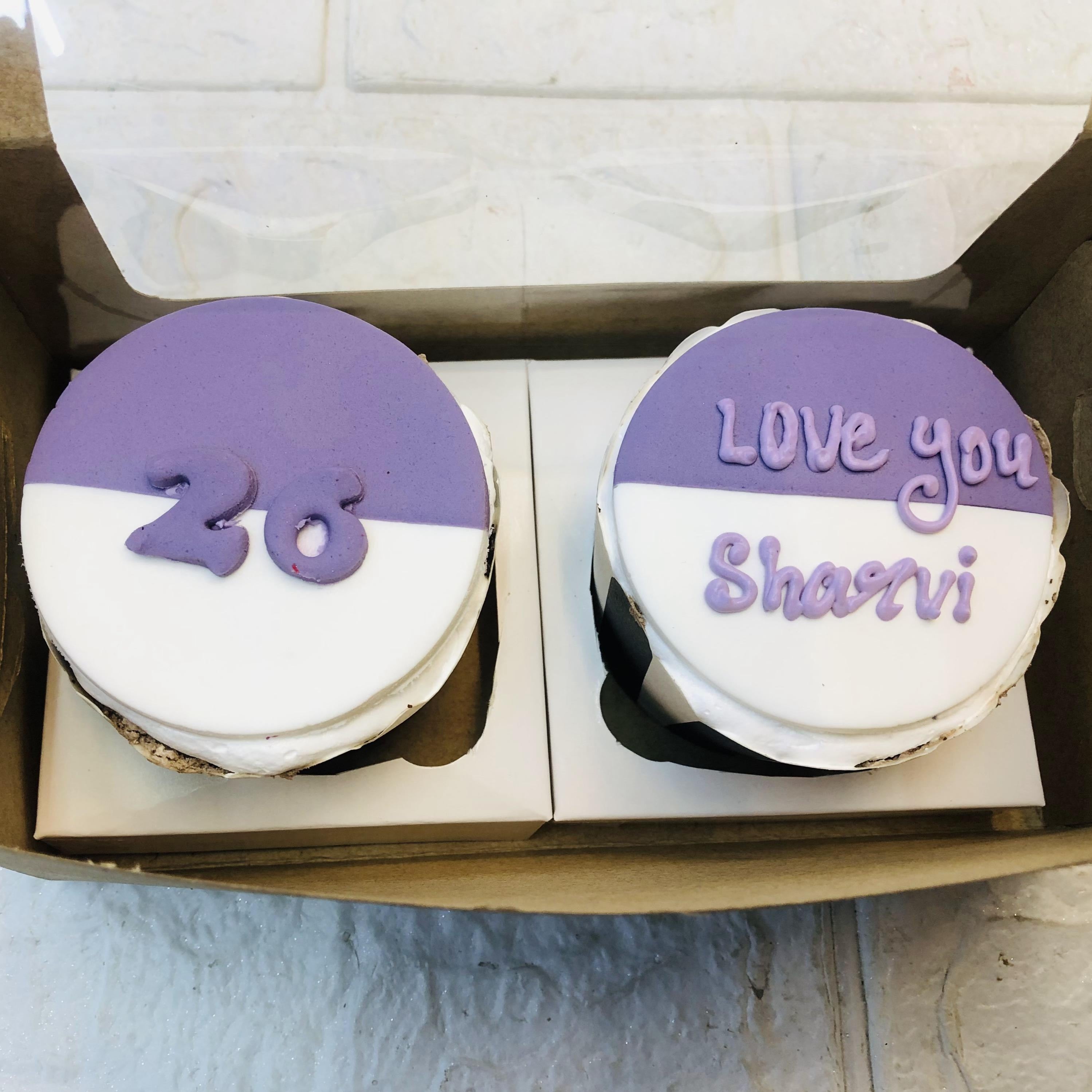  Two cupcakes adorned with purple and white frosting, elegantly displayed on a decorative plate.