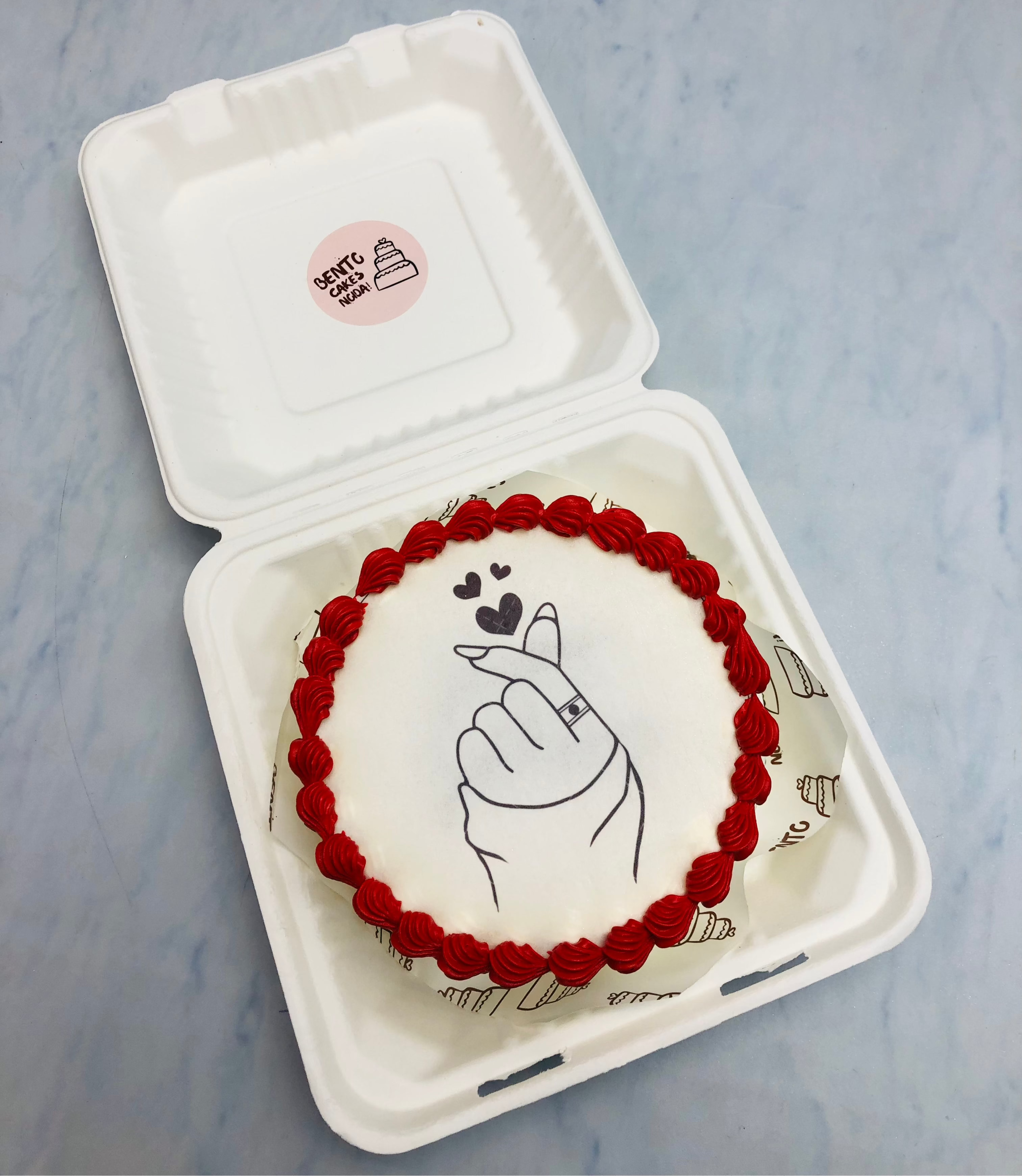 A white fire bento cake having a something love the mon fire paper and the bourdary decorated with red cream.