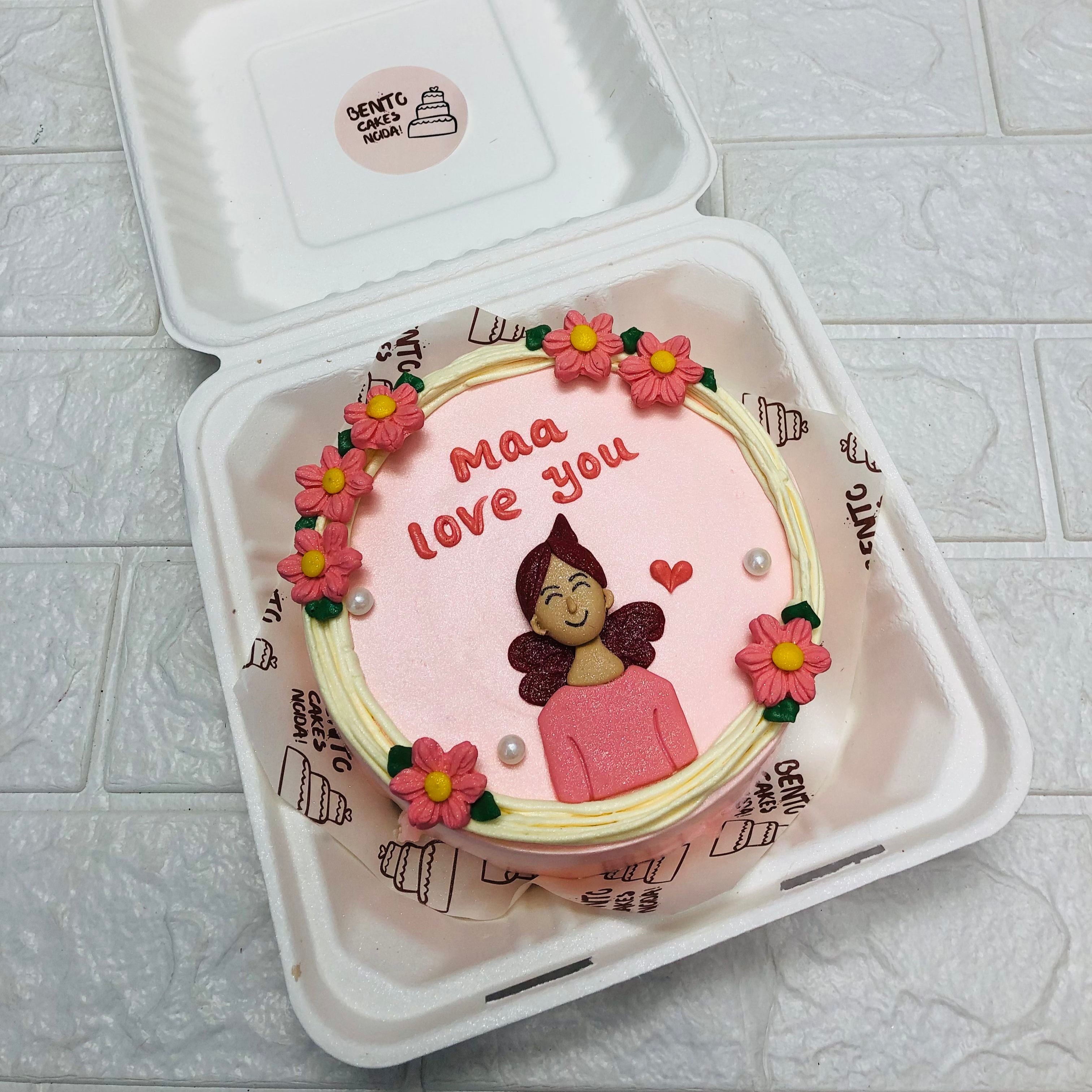 A light pink cake decorated with preety pink floral design on it and a beautiful mom designed with fondant on the cake with a text "Maa Love You" on it.