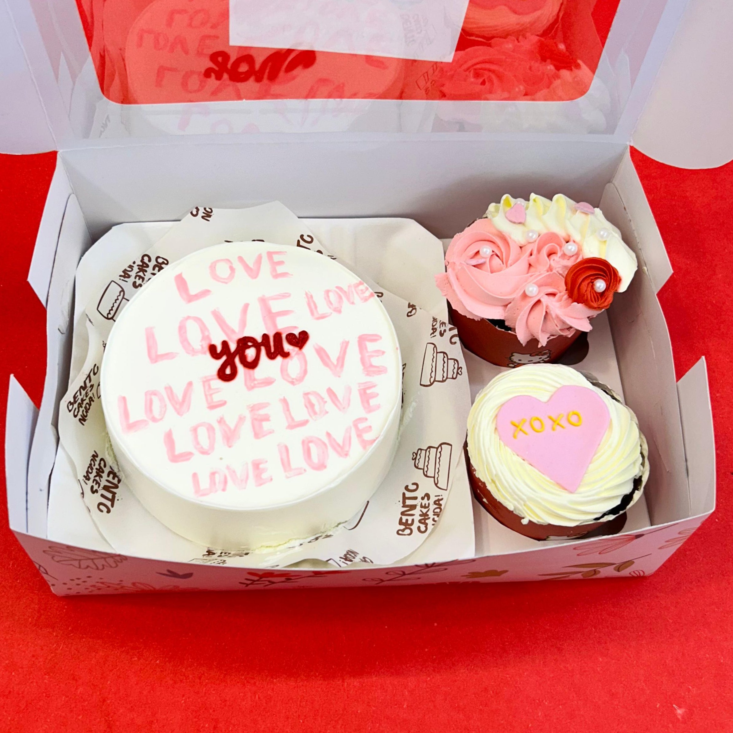 A box of Valentine's Day cupcakes featuring a mini bento combo cake with "Love You" decoration.