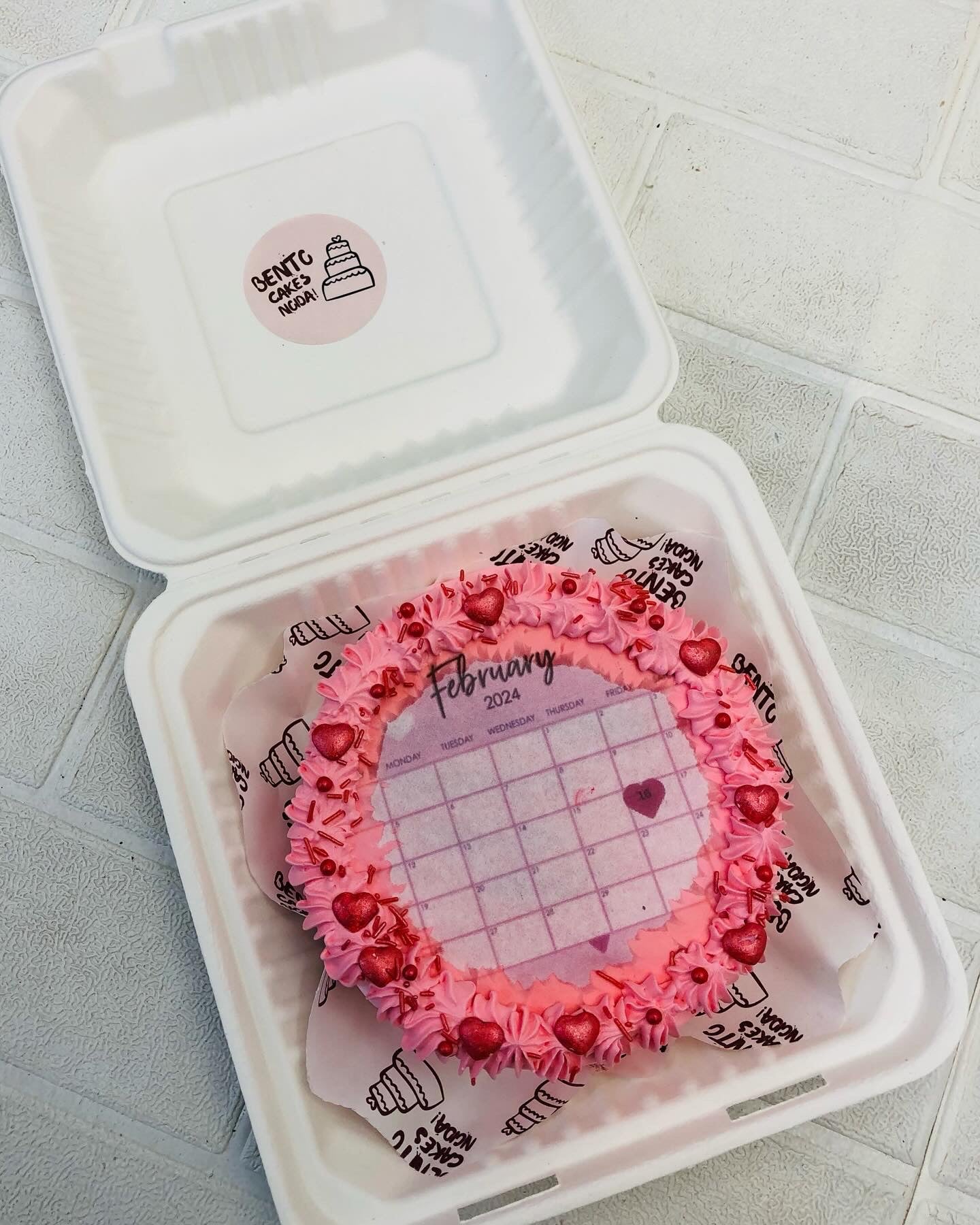 A lovely pink fire bento cake having february calendar print.