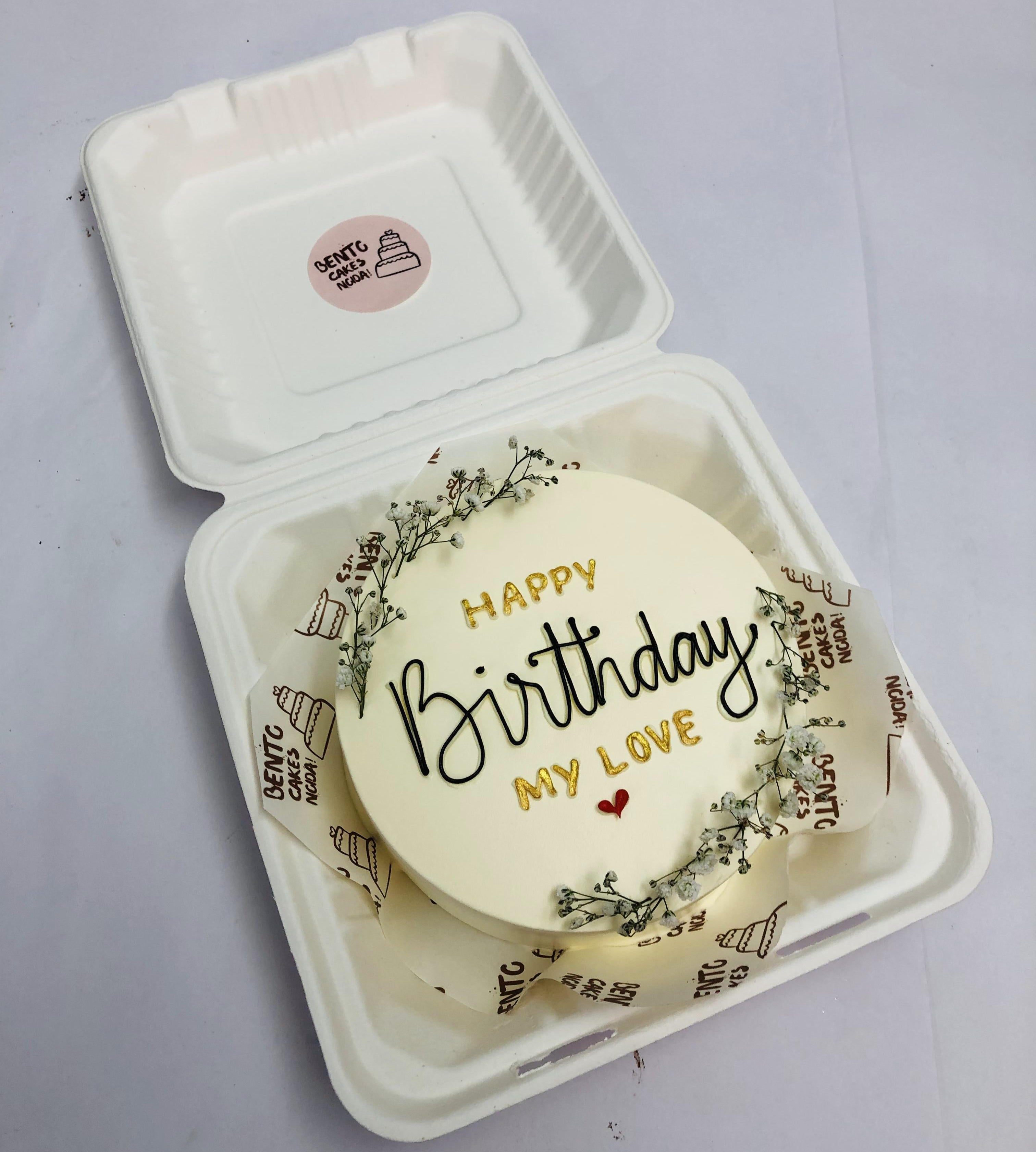 An aesthetic white bento cake decorated with vintage florals and a text "HAPPY Birthday MY LOVE" written with golden and black icing.