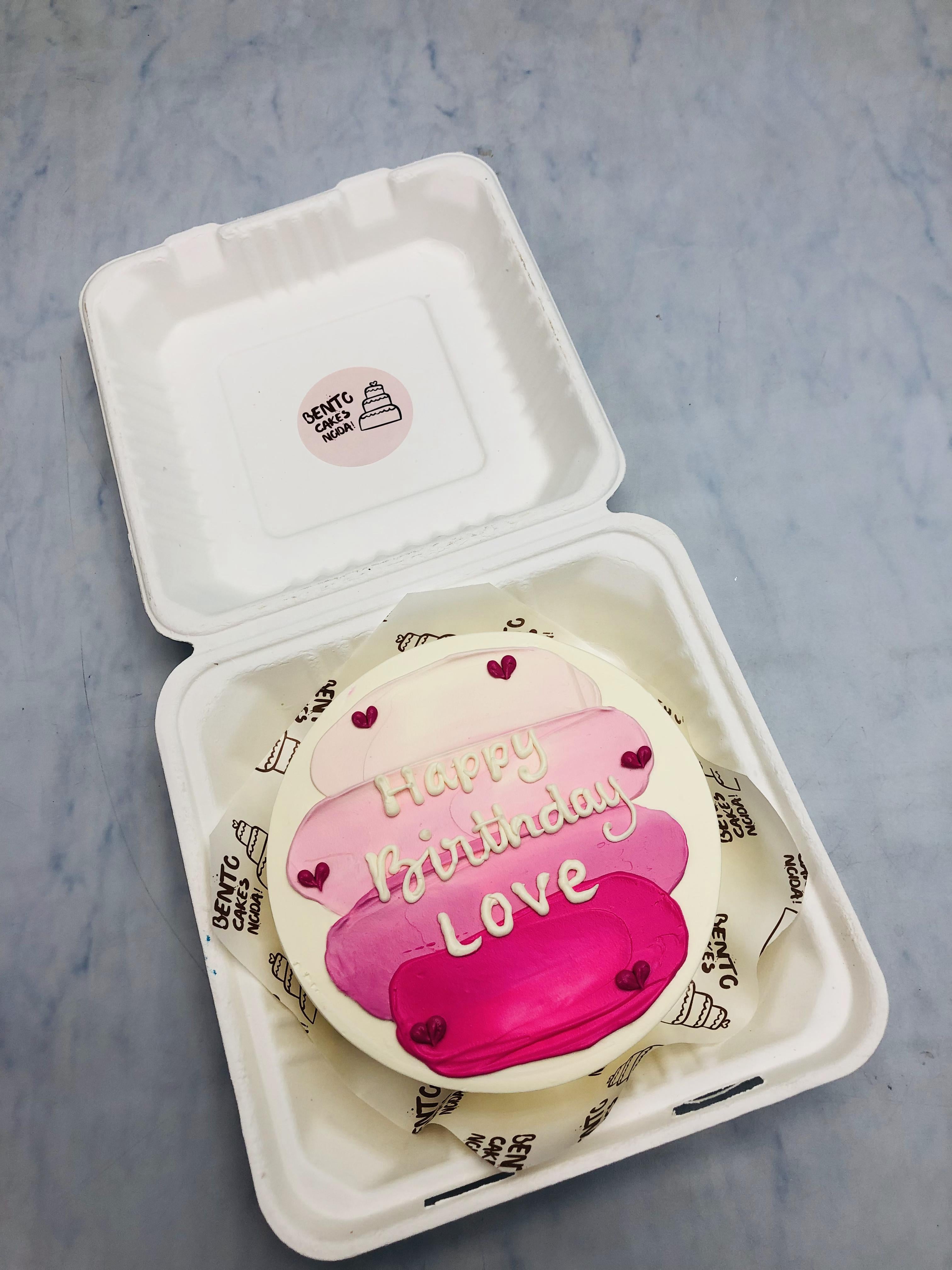 A 3 shades of pink color on off white cake with "Happy Birthday Love" written on it.