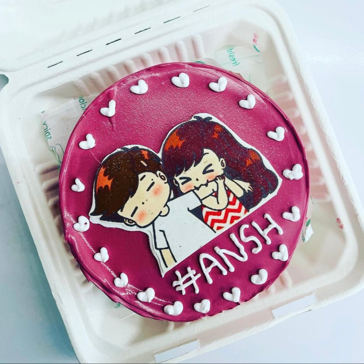 A beautifully decorated cake featuring a couple on top, presented in an elegant bento box.