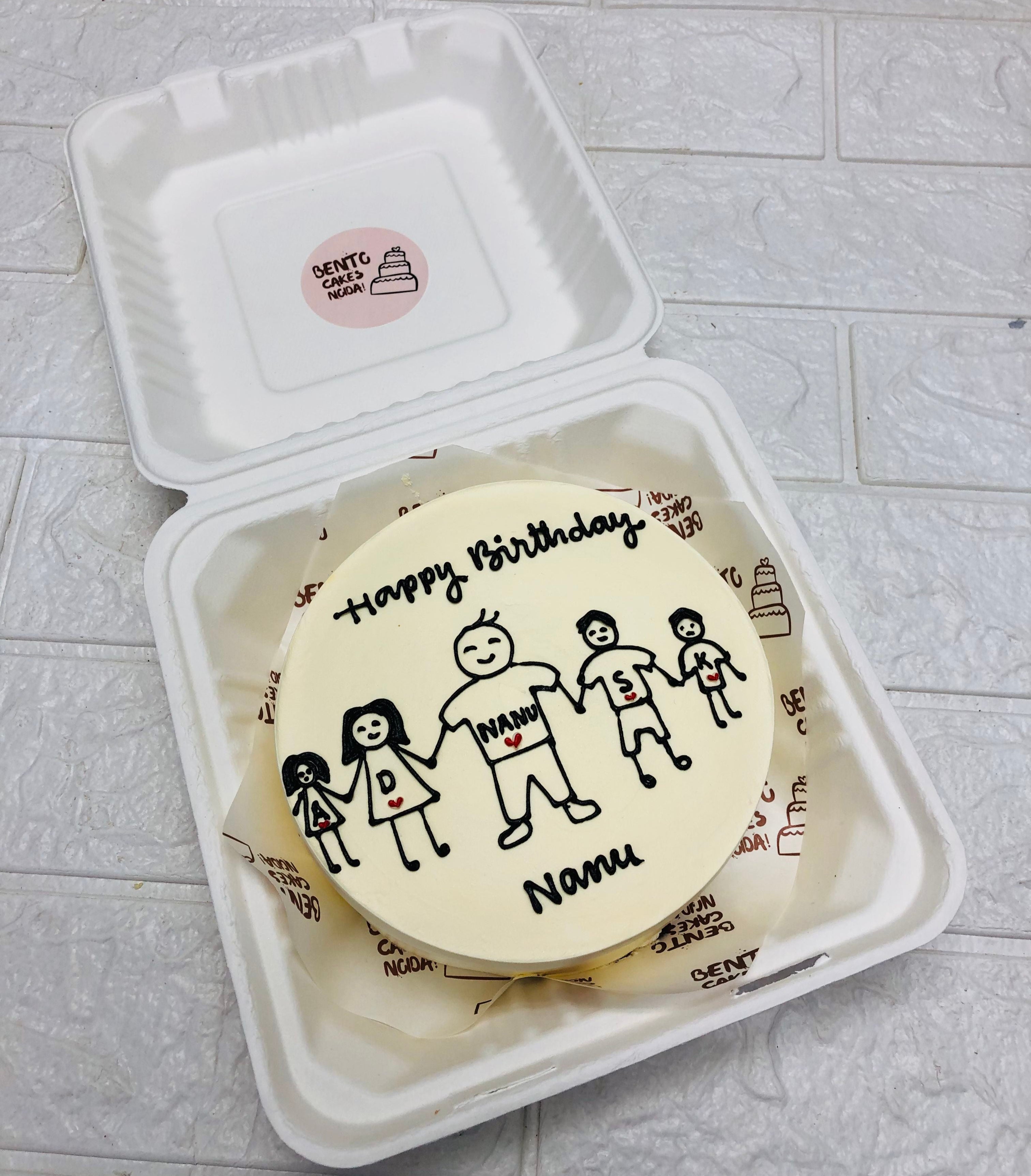 A cream color bento cake having a nanu with 4 grandsons drawing on it.