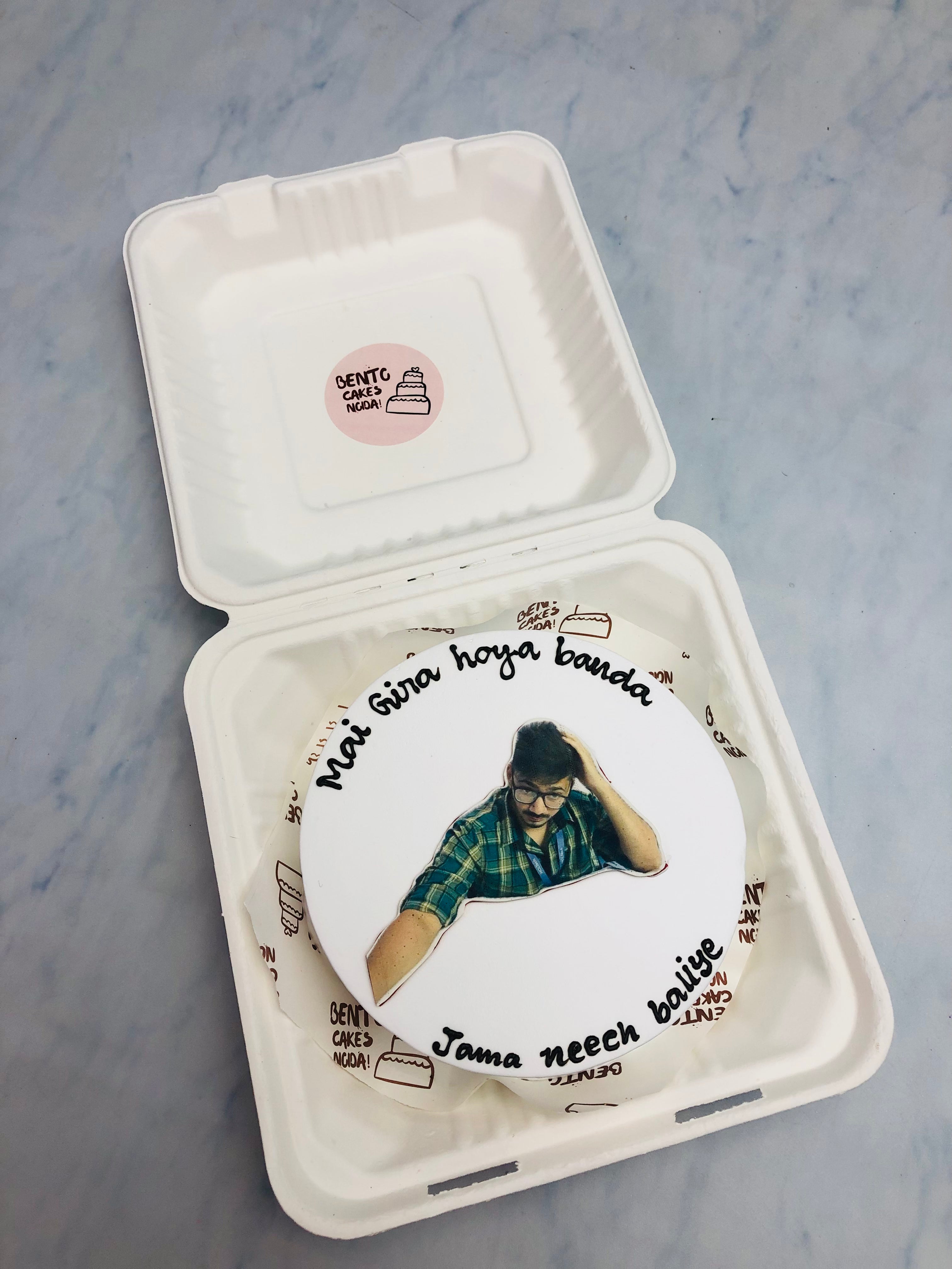 A white bento cake is designed with a mens photo clip and  song text written on it.