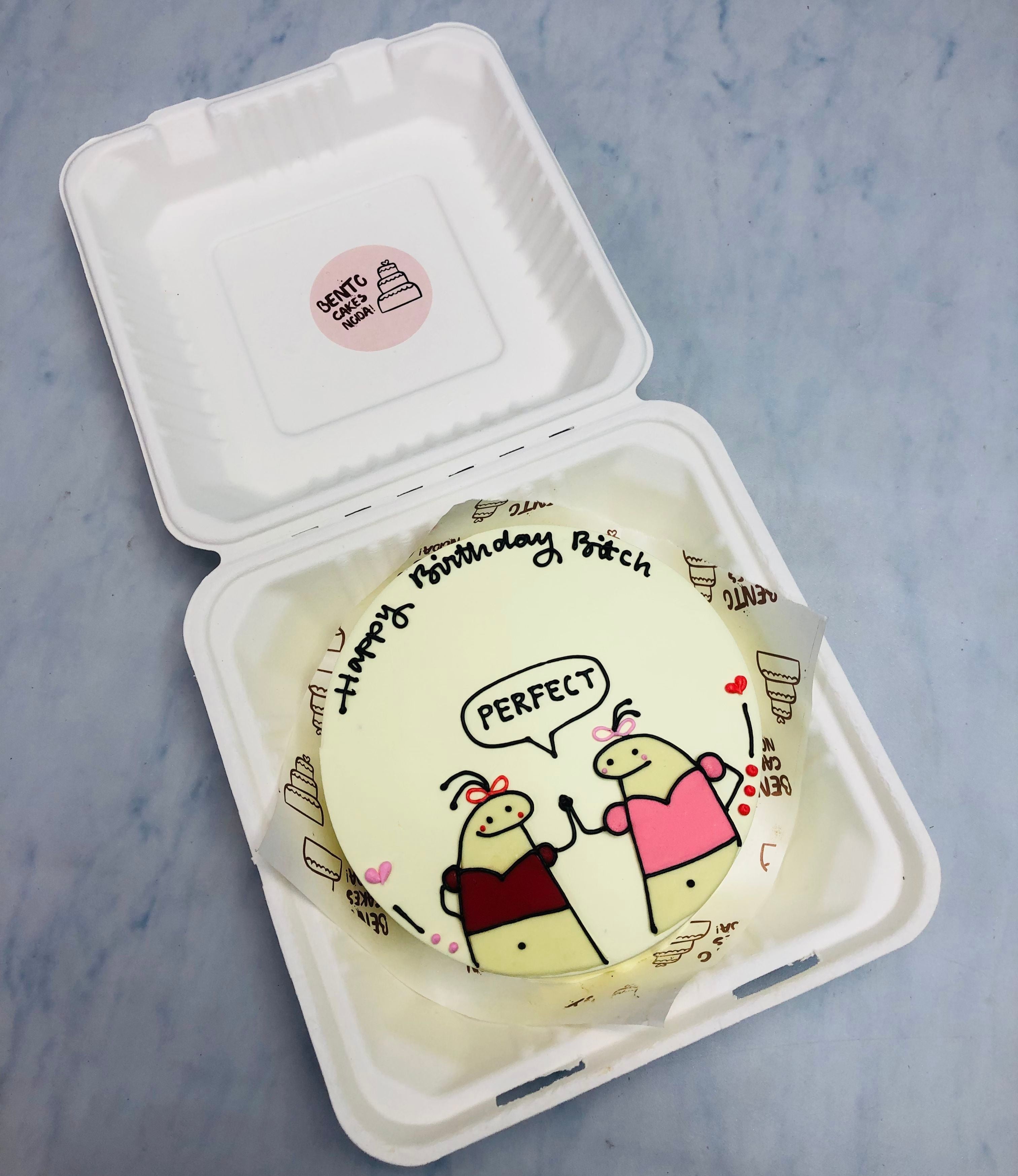 A round birthday cake with white frosting, featuring two cartoon characters holding hands. The cake includes text that reads 'Happy Birthday Bitch' and 'Perfect'