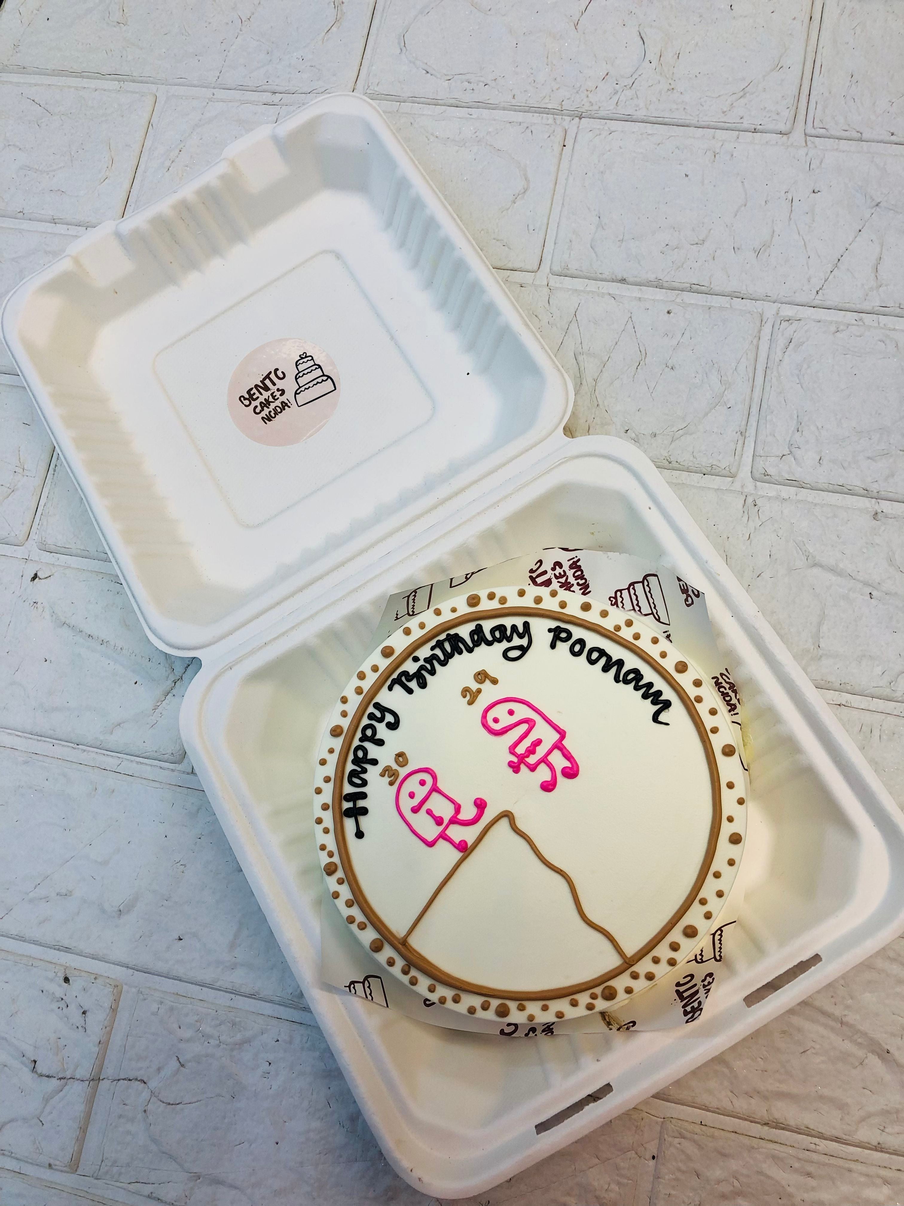 A white cake with pink mimi design ond surrounded white brown icing.