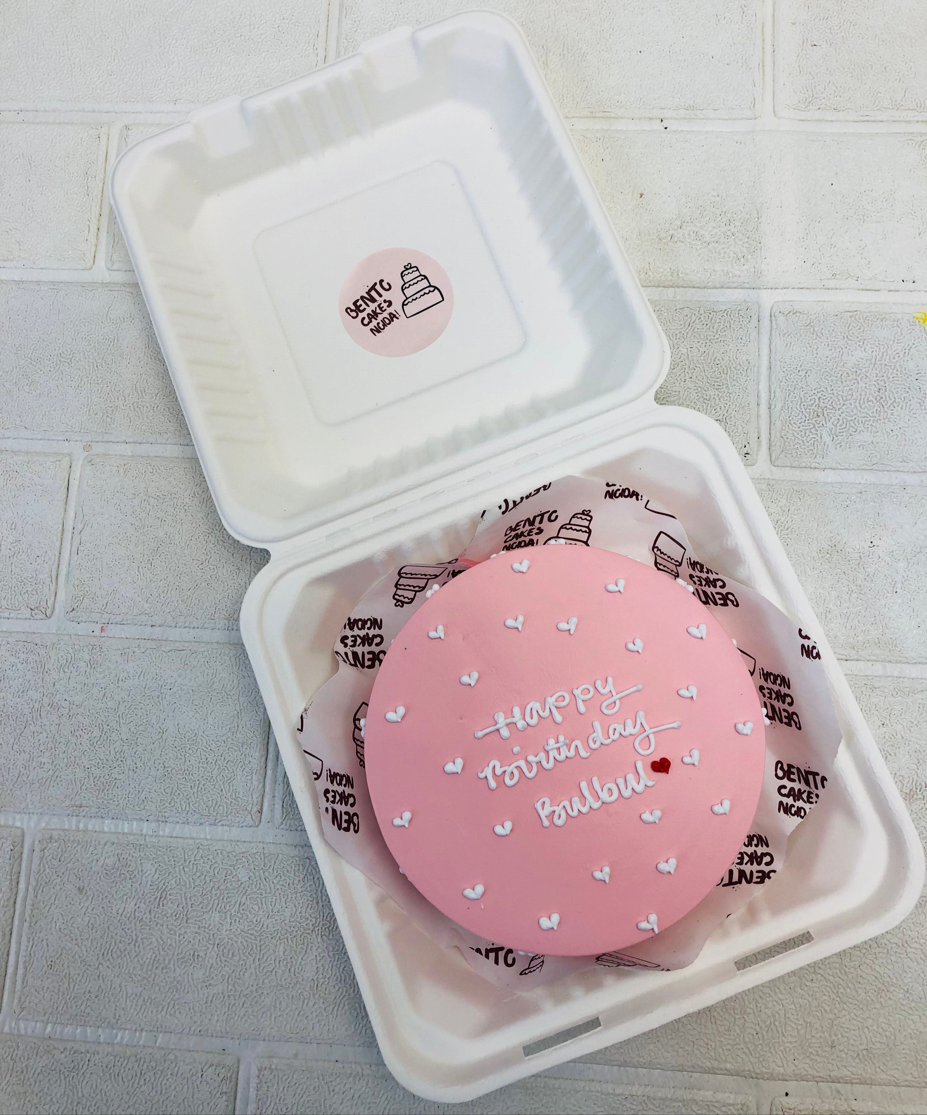 A minimalist rose gold bento cake for birthday, filled with little white hearts.