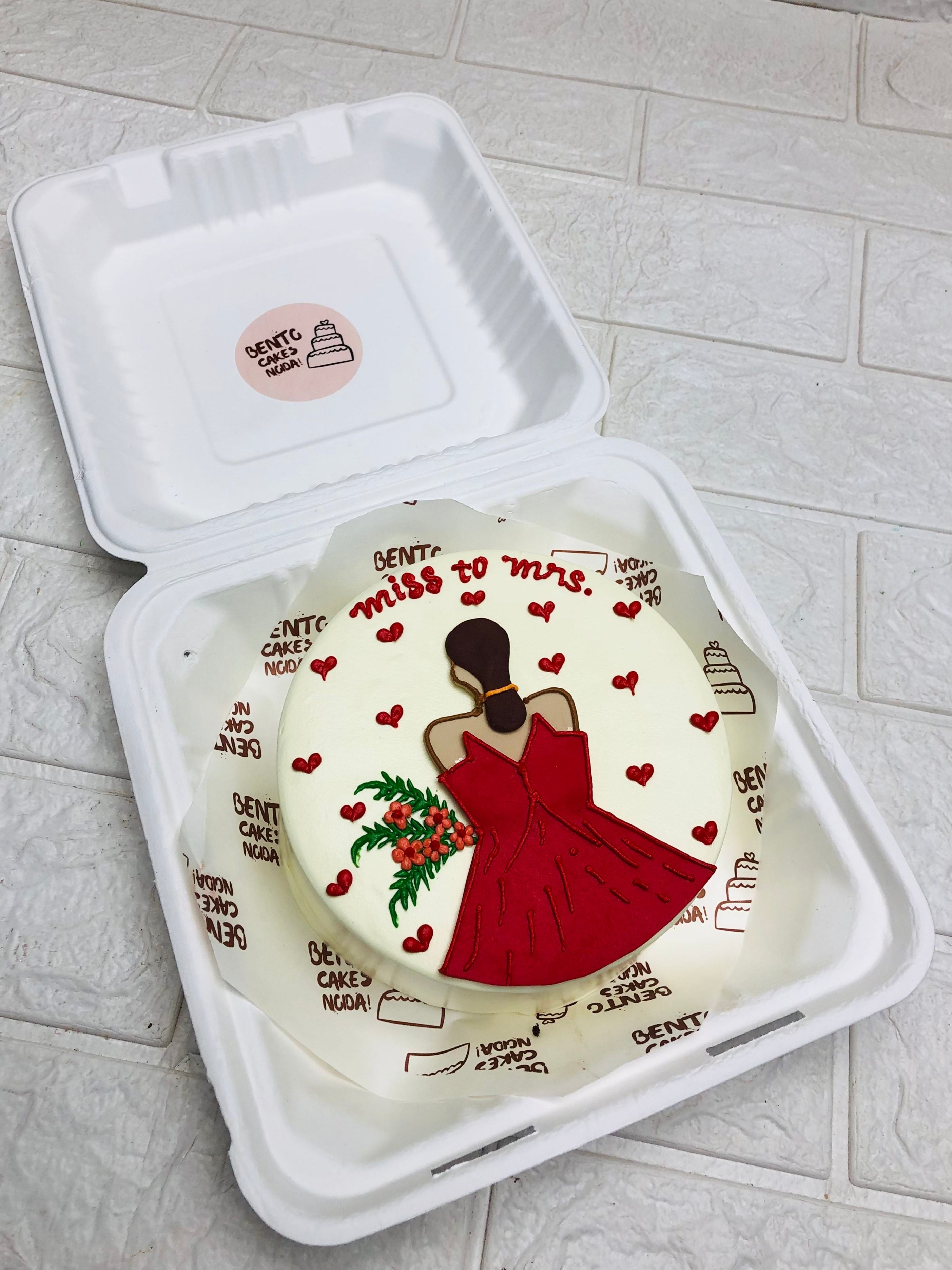An offwhite cake with a bridle girl design in red dress and cake decorated with red hearts.