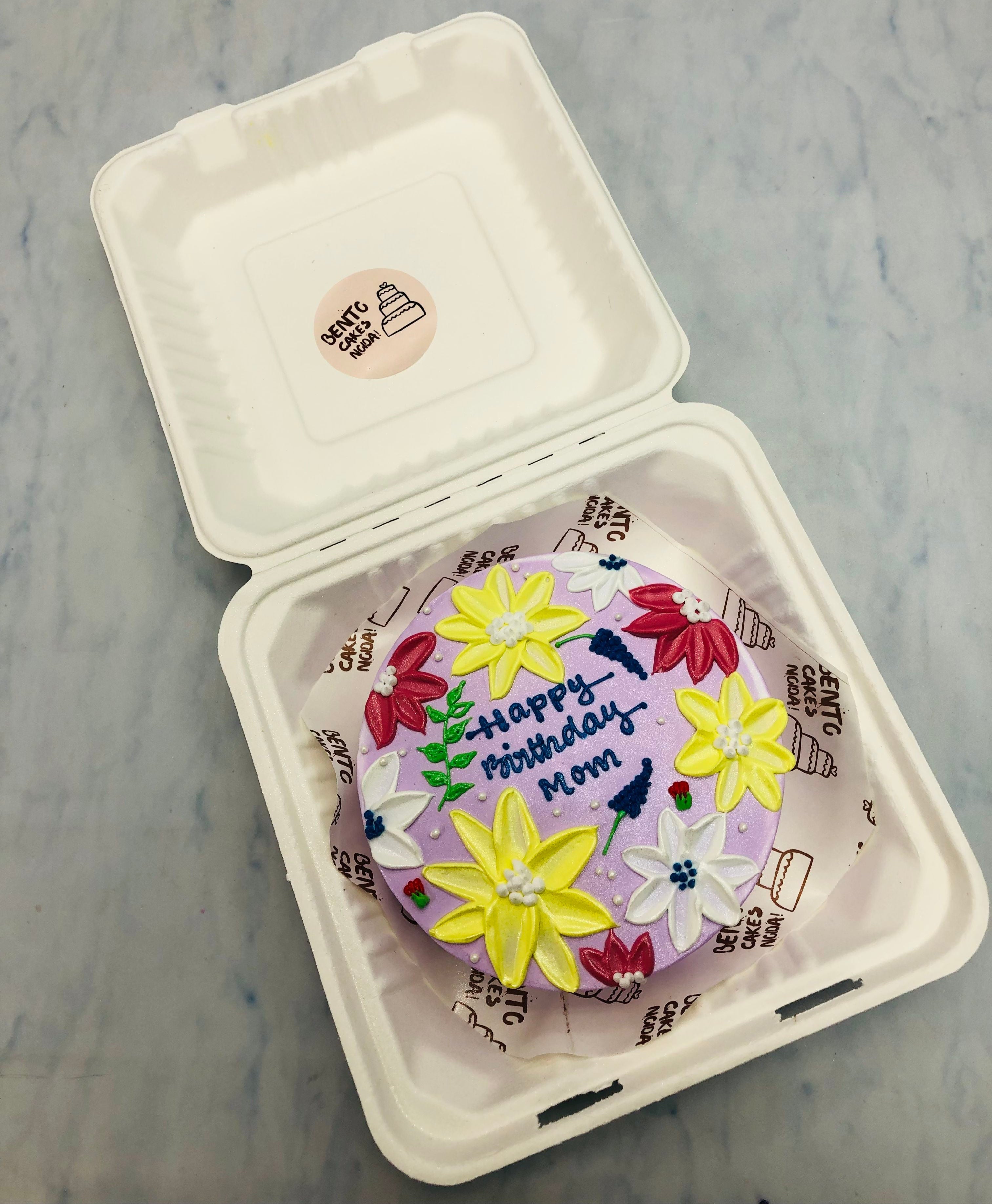 A light purple bento cake havingb colorful florals design for moms birthday.
