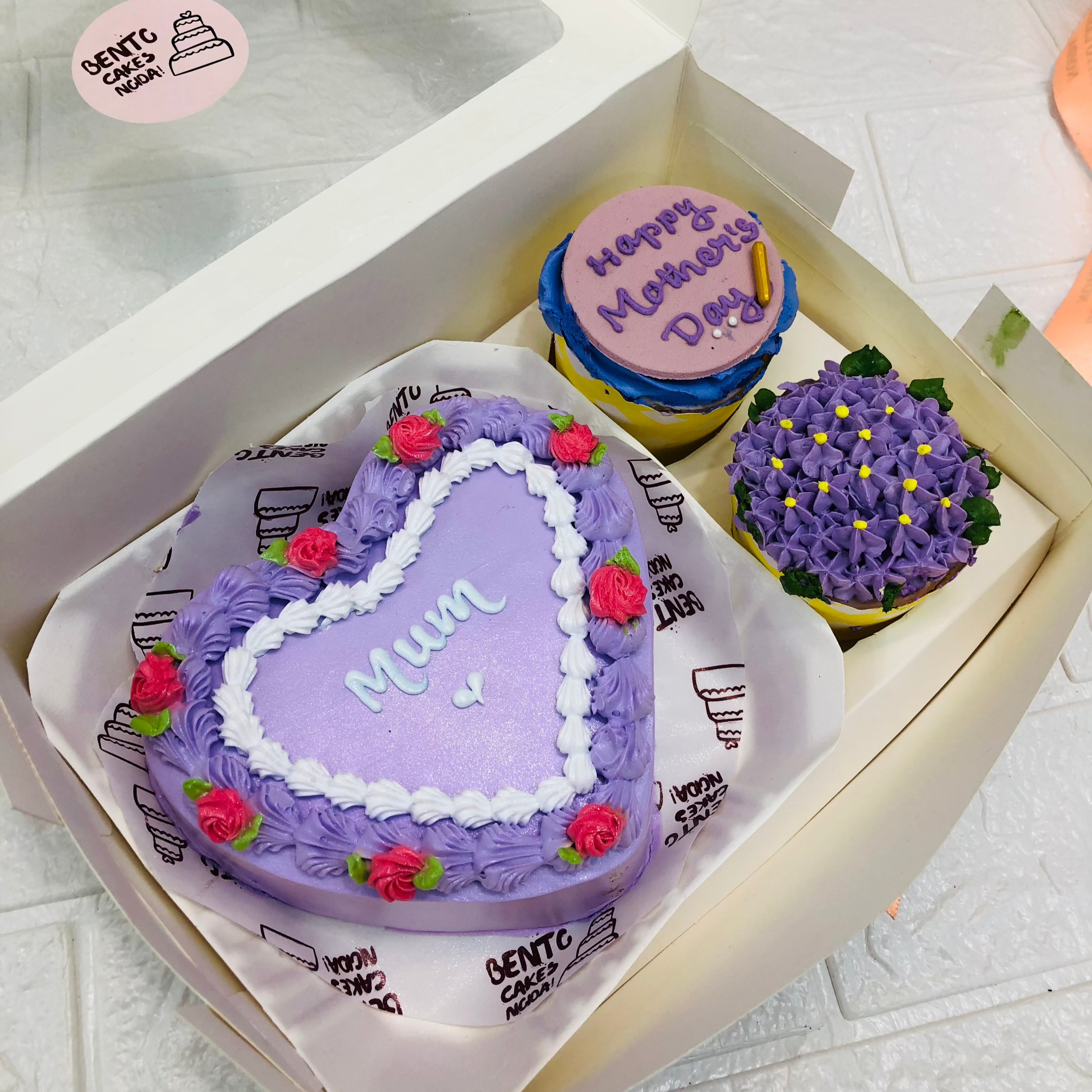 A mini bento combo having 1 cake and 2 cupcakes set. A purple color heart shape cake have beautiful floral deign and cupcakes having dark purple floral and fondant design.