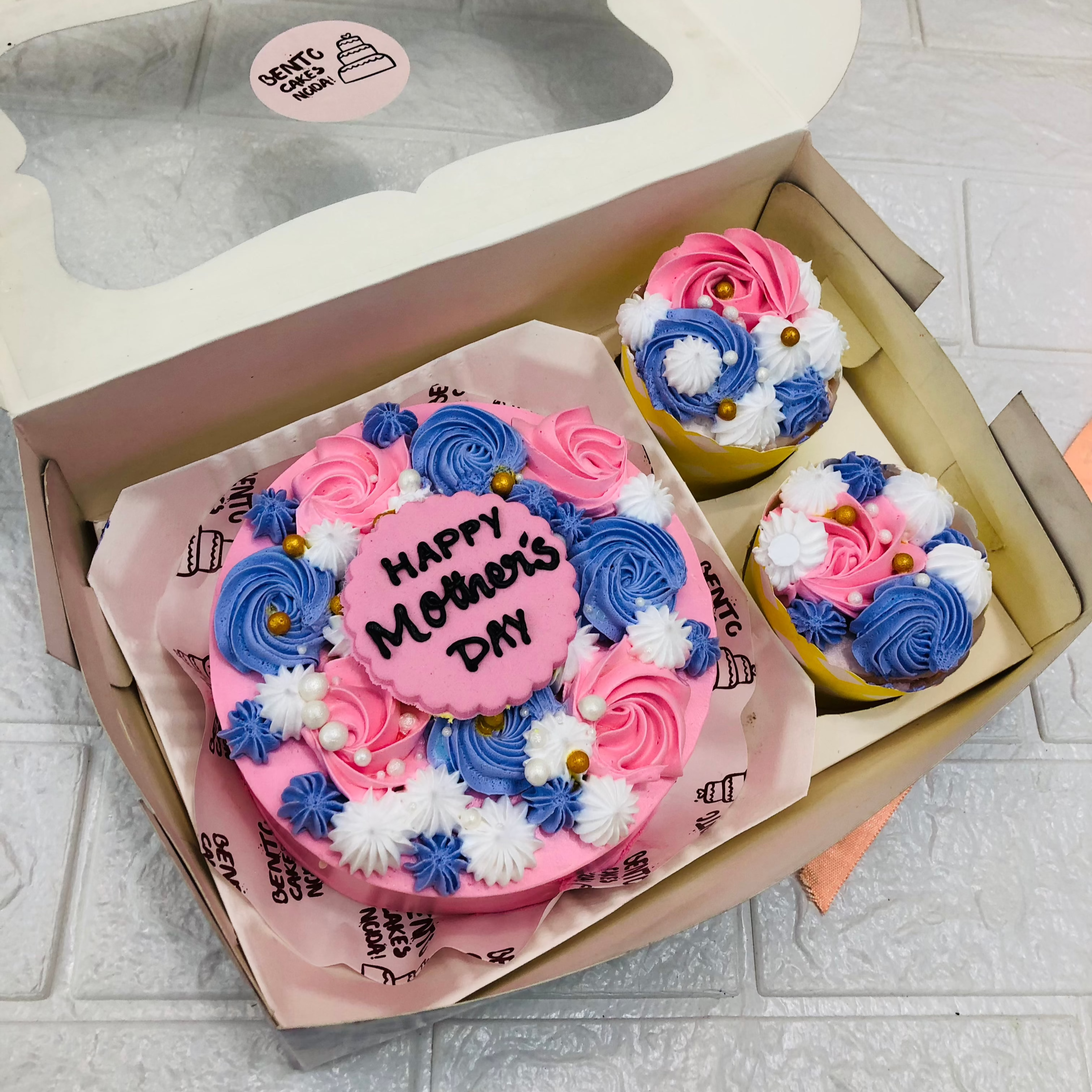 A mini bento combo having 1 cake and 2 cupcakes set. A pink color round cake haveing beautiful florals deign and cupcakes having colorful floral design.
