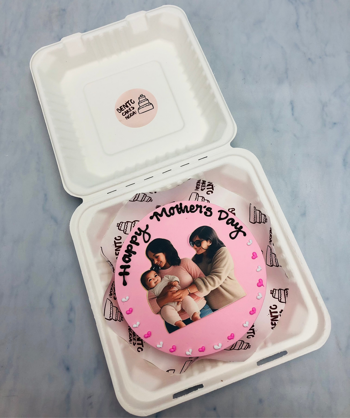 A pink bento cake having a family photo theme for mothers day celebration.