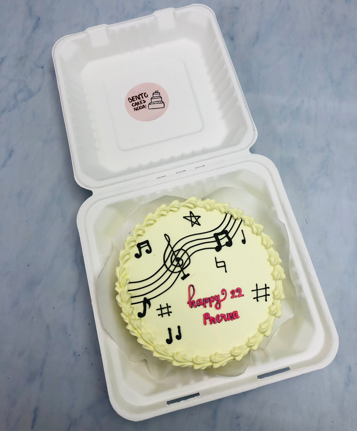 An offwhite bento cake for a music lovers birthday and designed with music tunes.