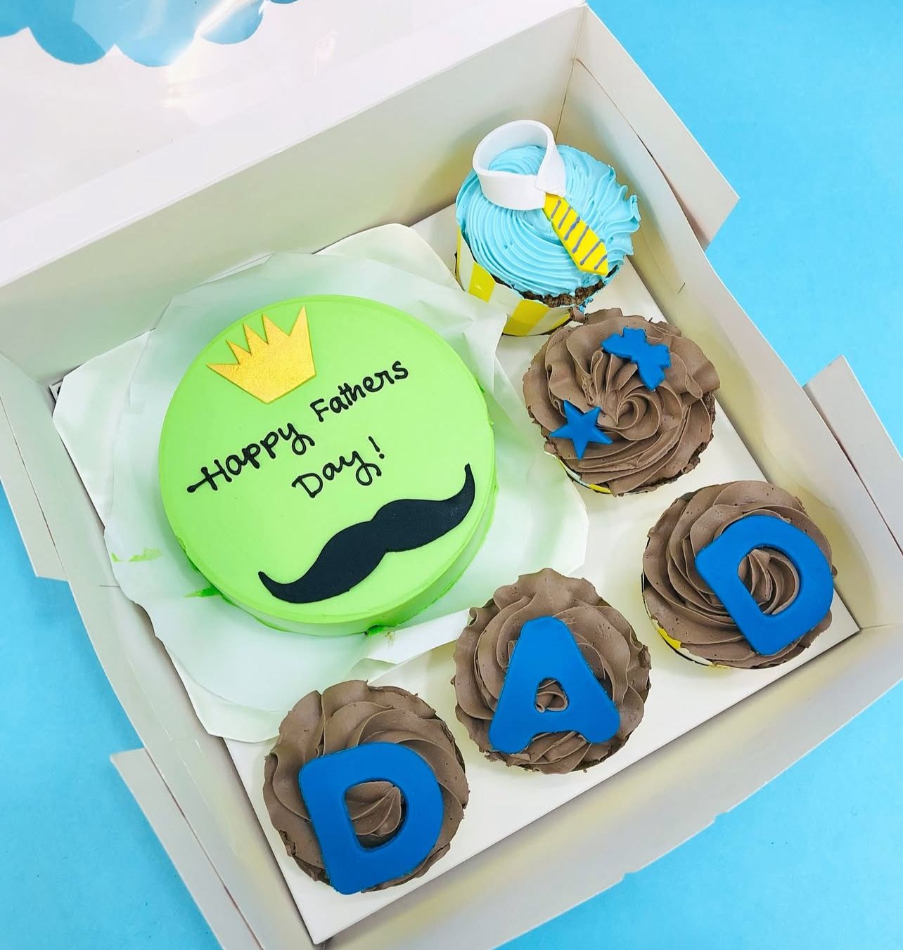 A green bento cake having mustaque design and happy fathere day text and 5 cupcakes with different designs.