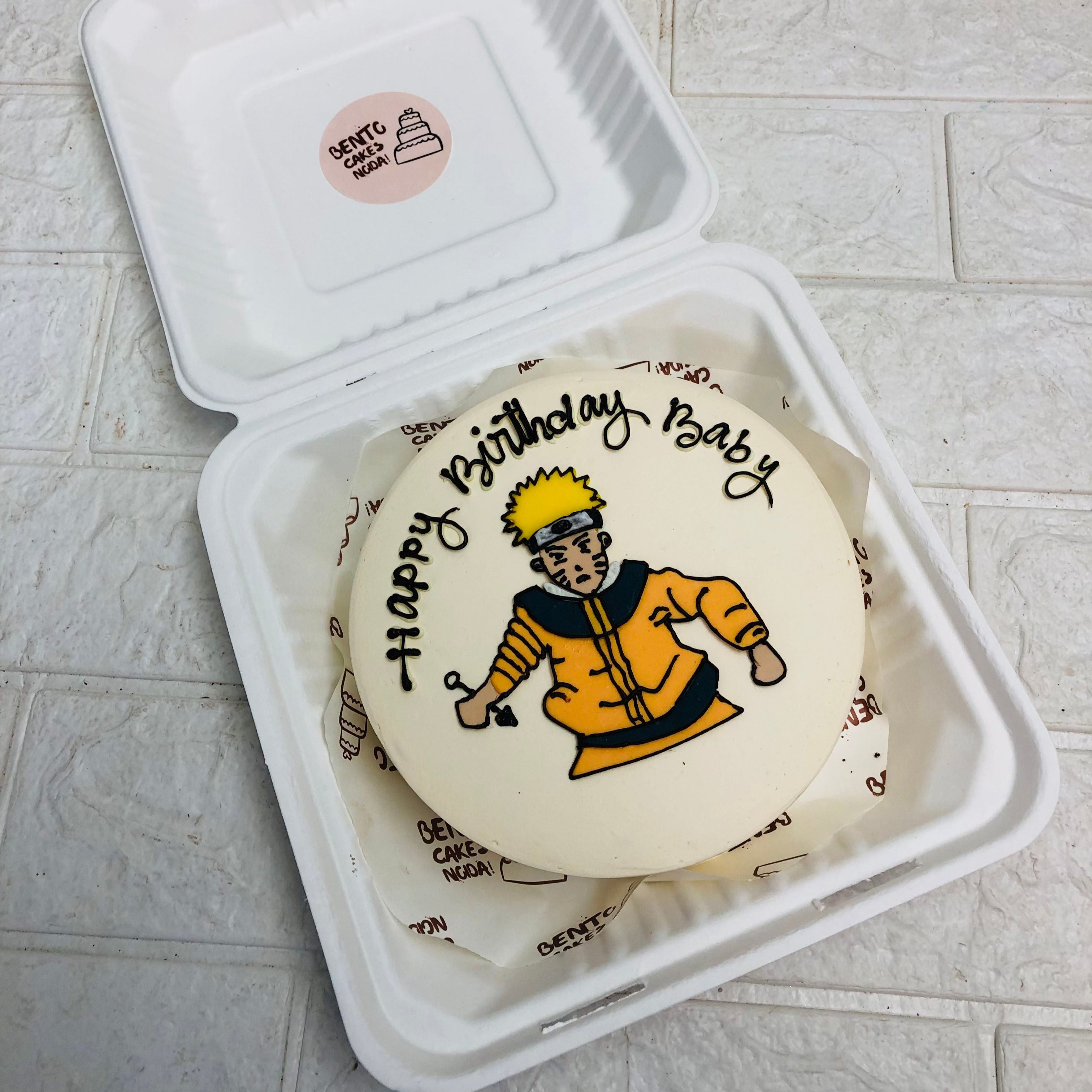  A birthday cake in a box featuring a colorful Naruto cartoon character design on the top, ready for birthday celebration.