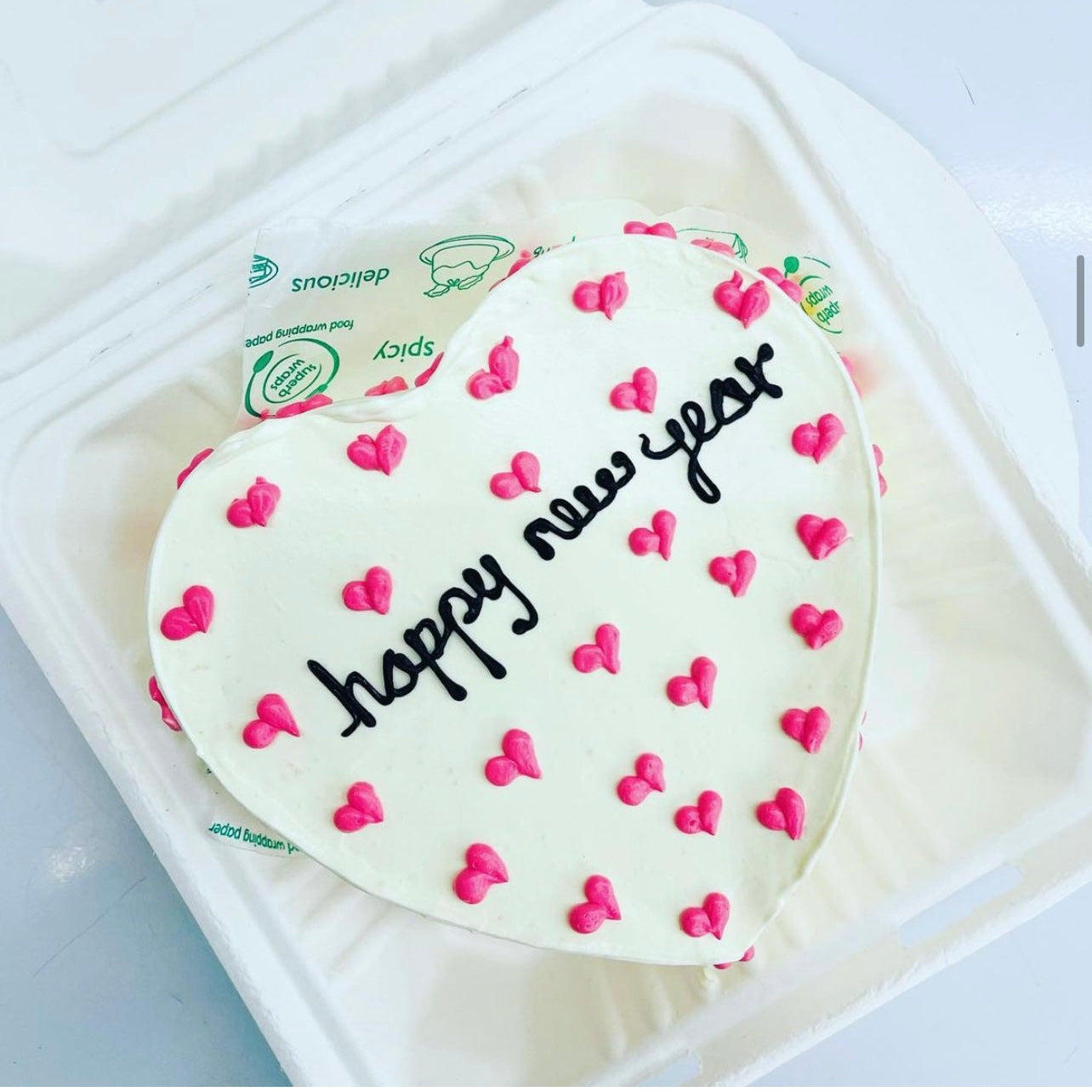 A white box containing a heart-shaped cake, elegantly presented for a special occasion.