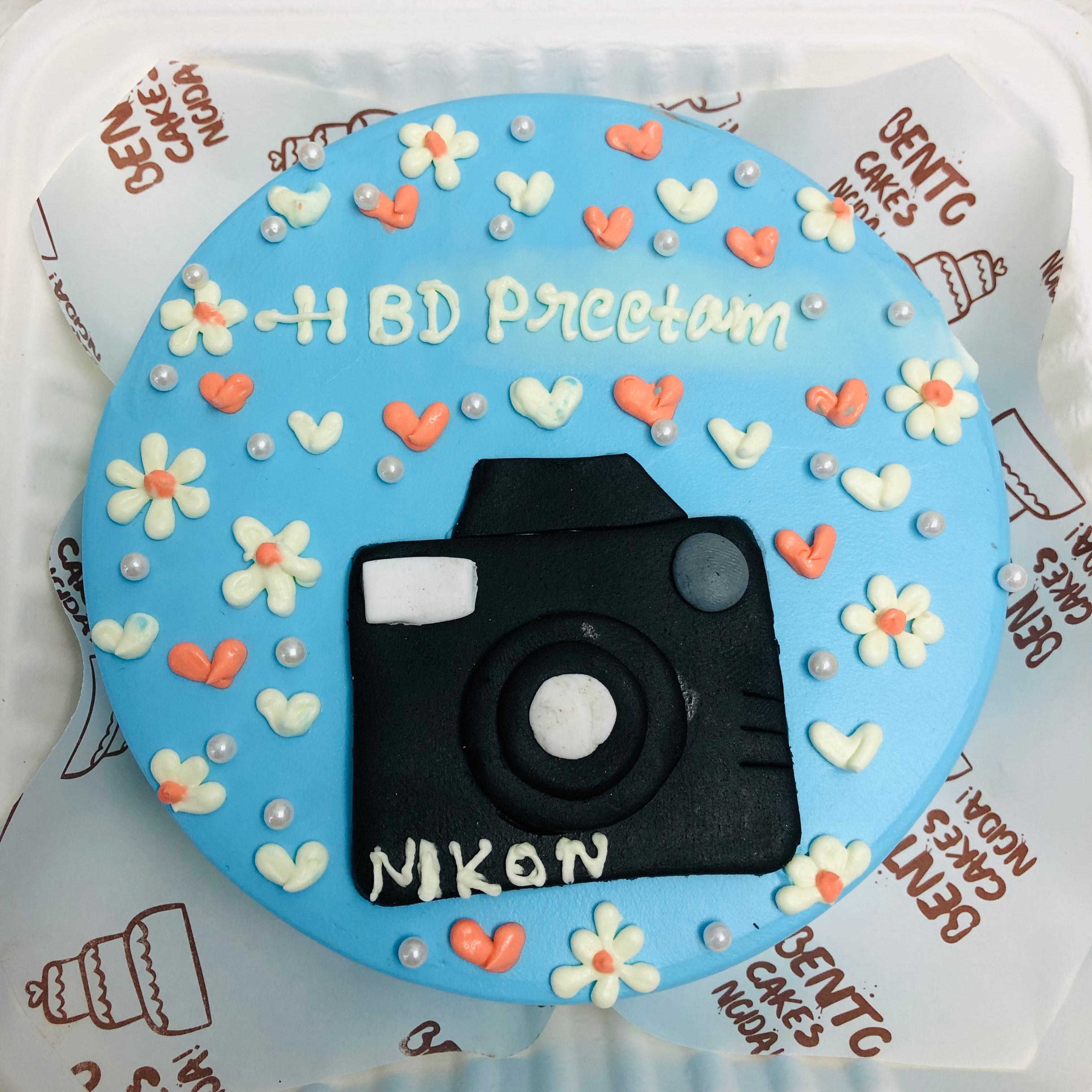 A floral blue bento cake is designed with nikon camera for birthday.