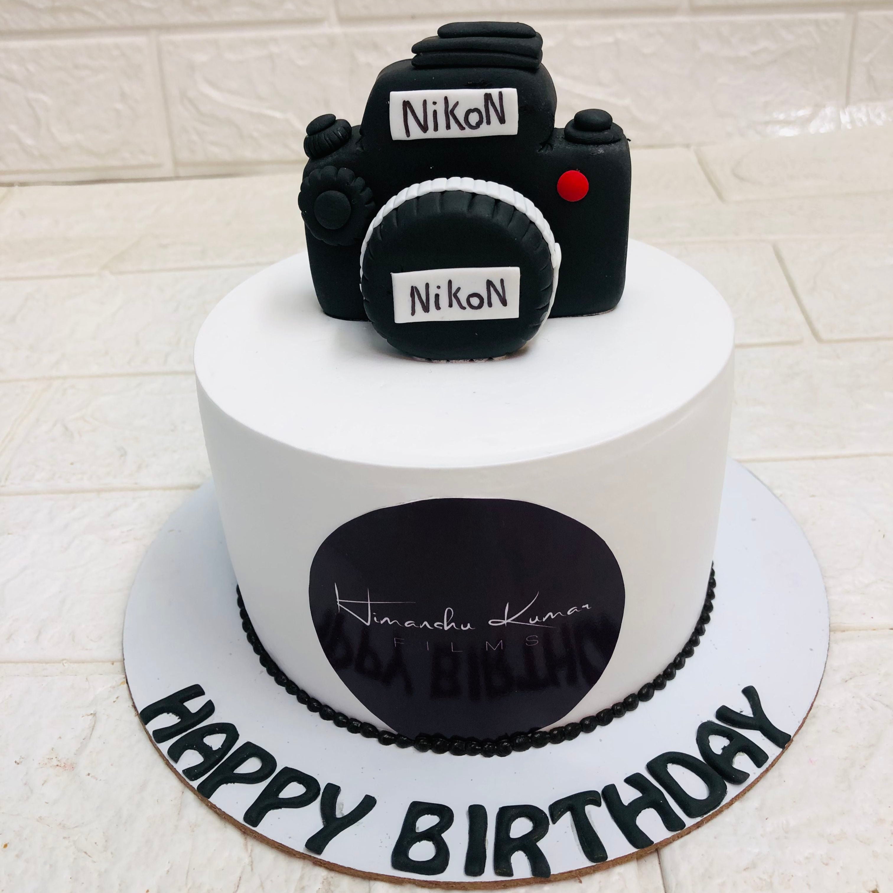 A festive birthday cake adorned with a camera on top, symbolizing a celebration of memories captured.