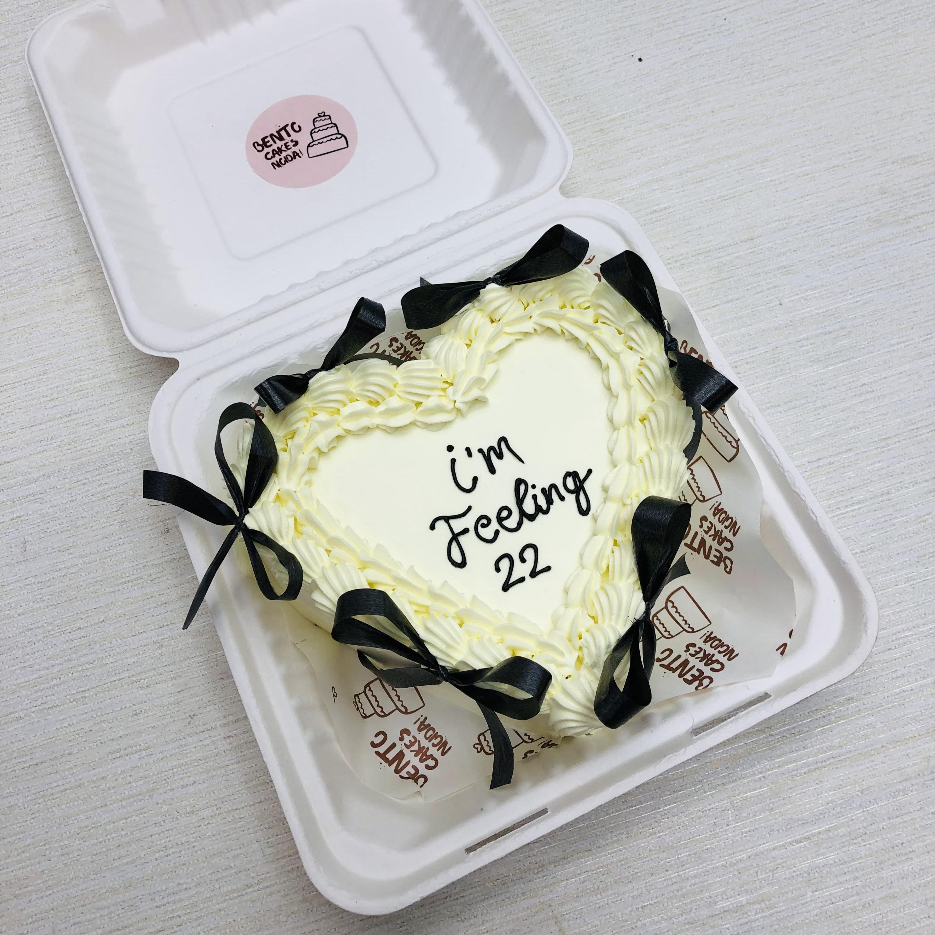 A Off White Heart Bento Cake with black bows and  txt written with black icing.