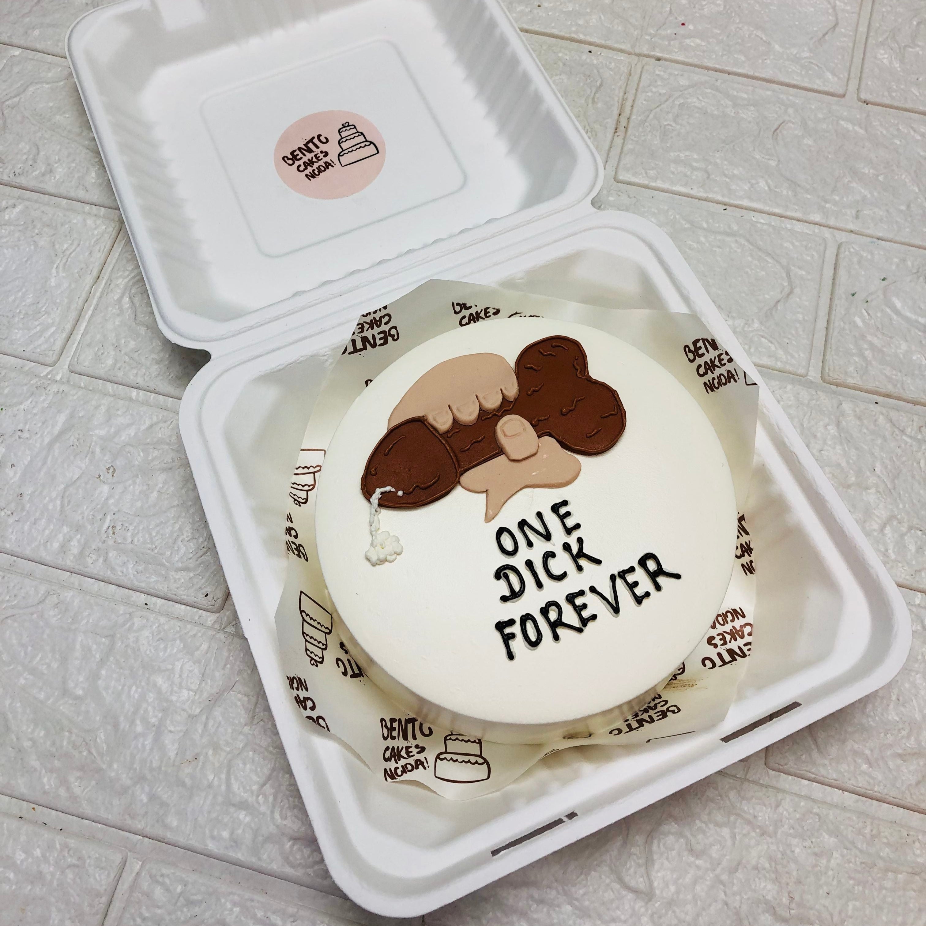 A white bento cake with a hand hoding a dick.