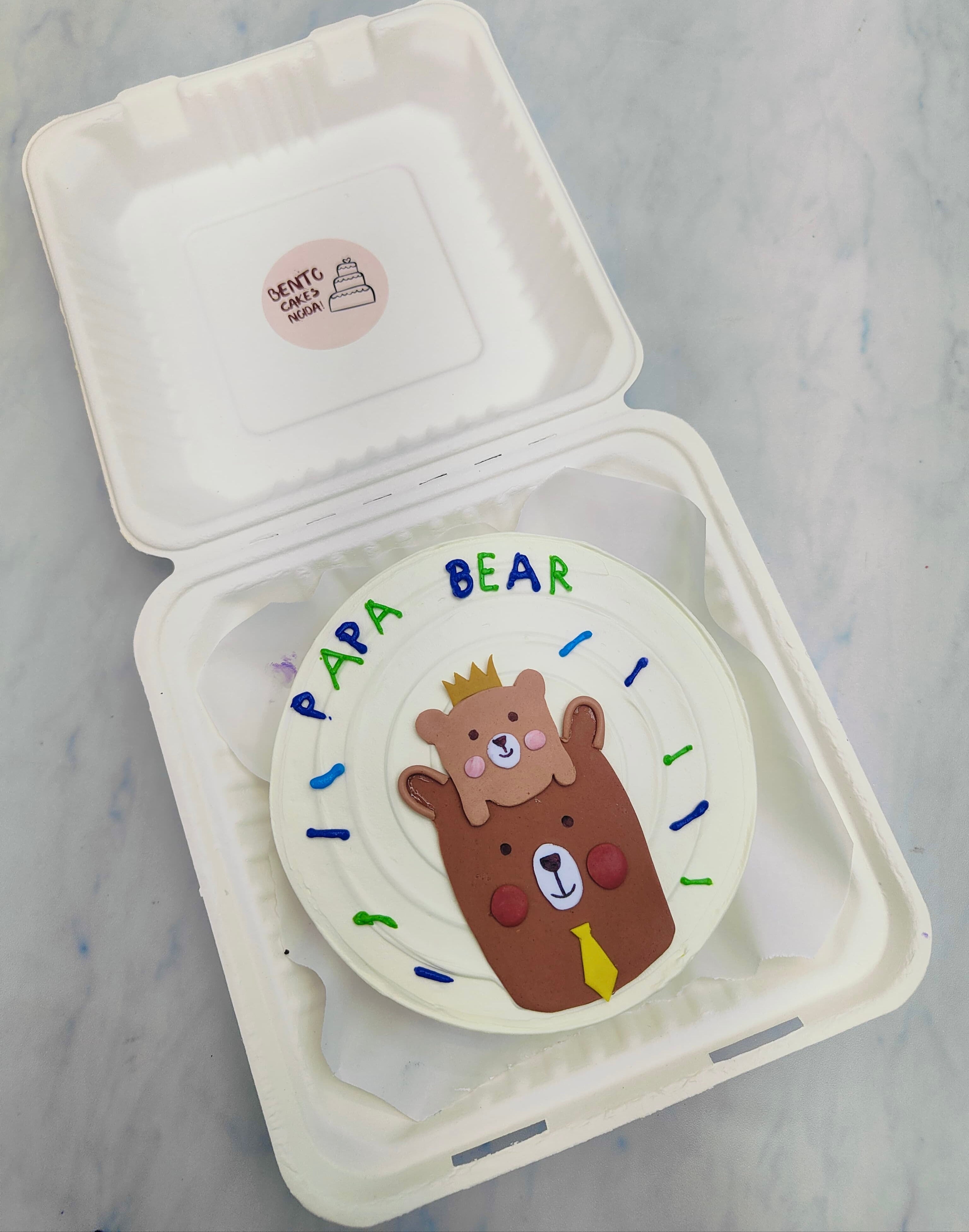 A white bento cake is designed for father and havig a fondant bear with his child bear.