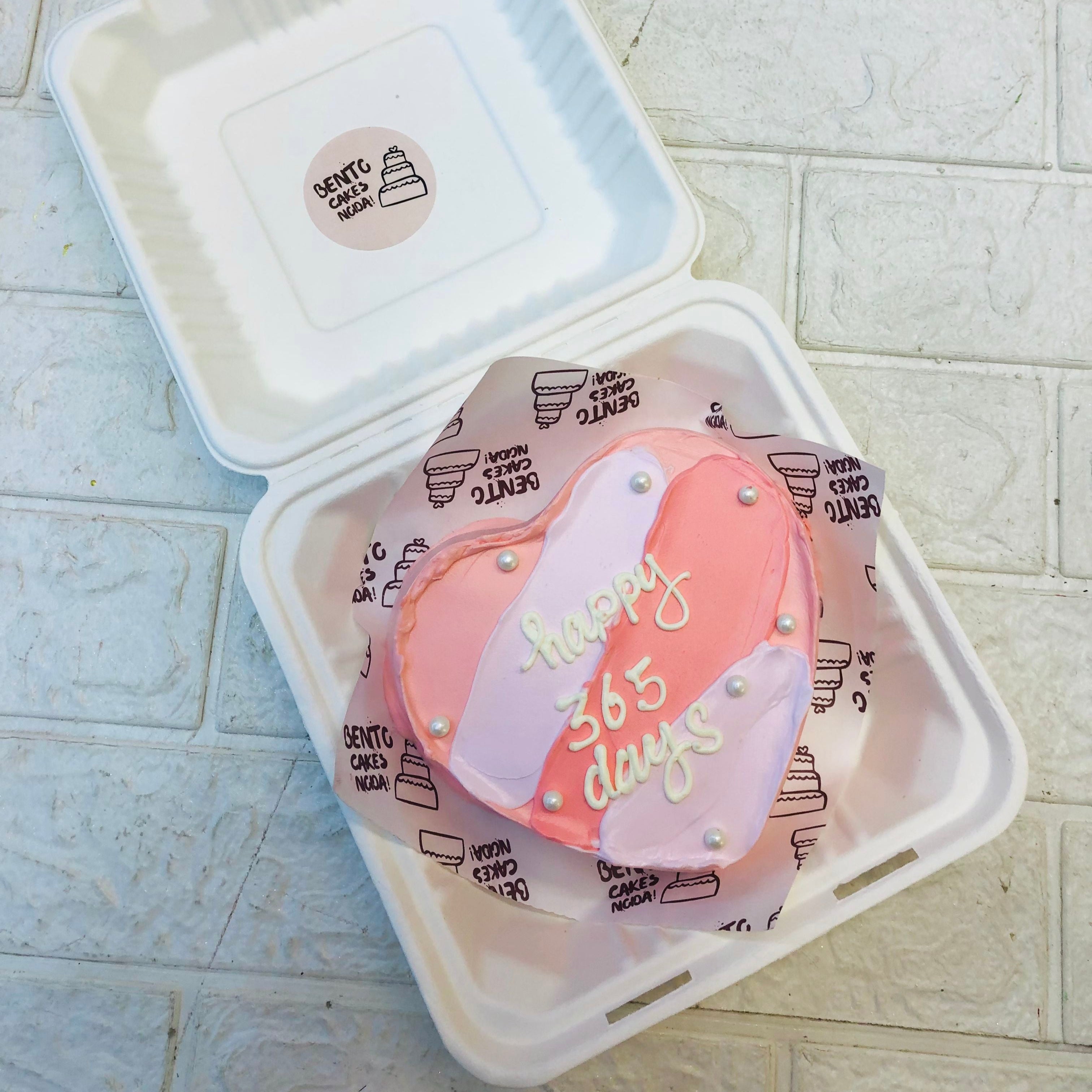 A pastle pink and grey heart shape cake with a loving text on it.