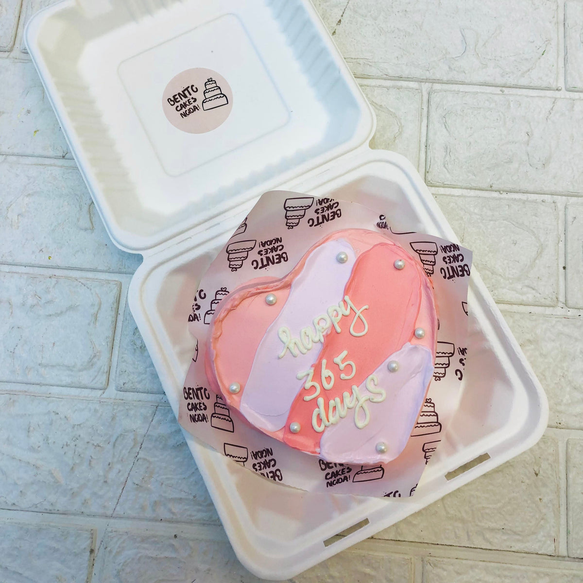 A pastle pink and grey heart shape cake with a loving text on it.