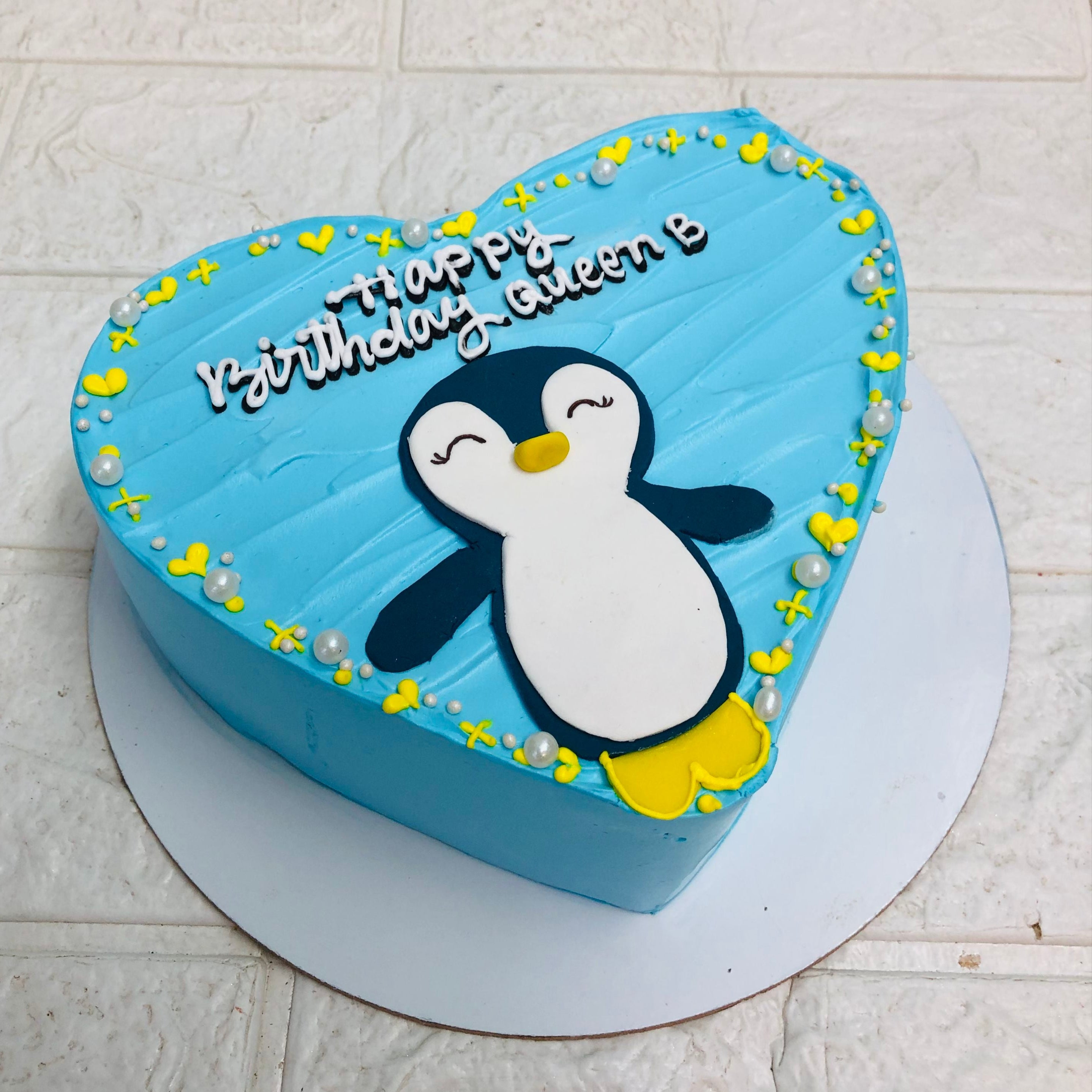 A delightful penguin-shaped cake adorned with a cheerful "Happy Birthday" message, perfect for a festive celebration.