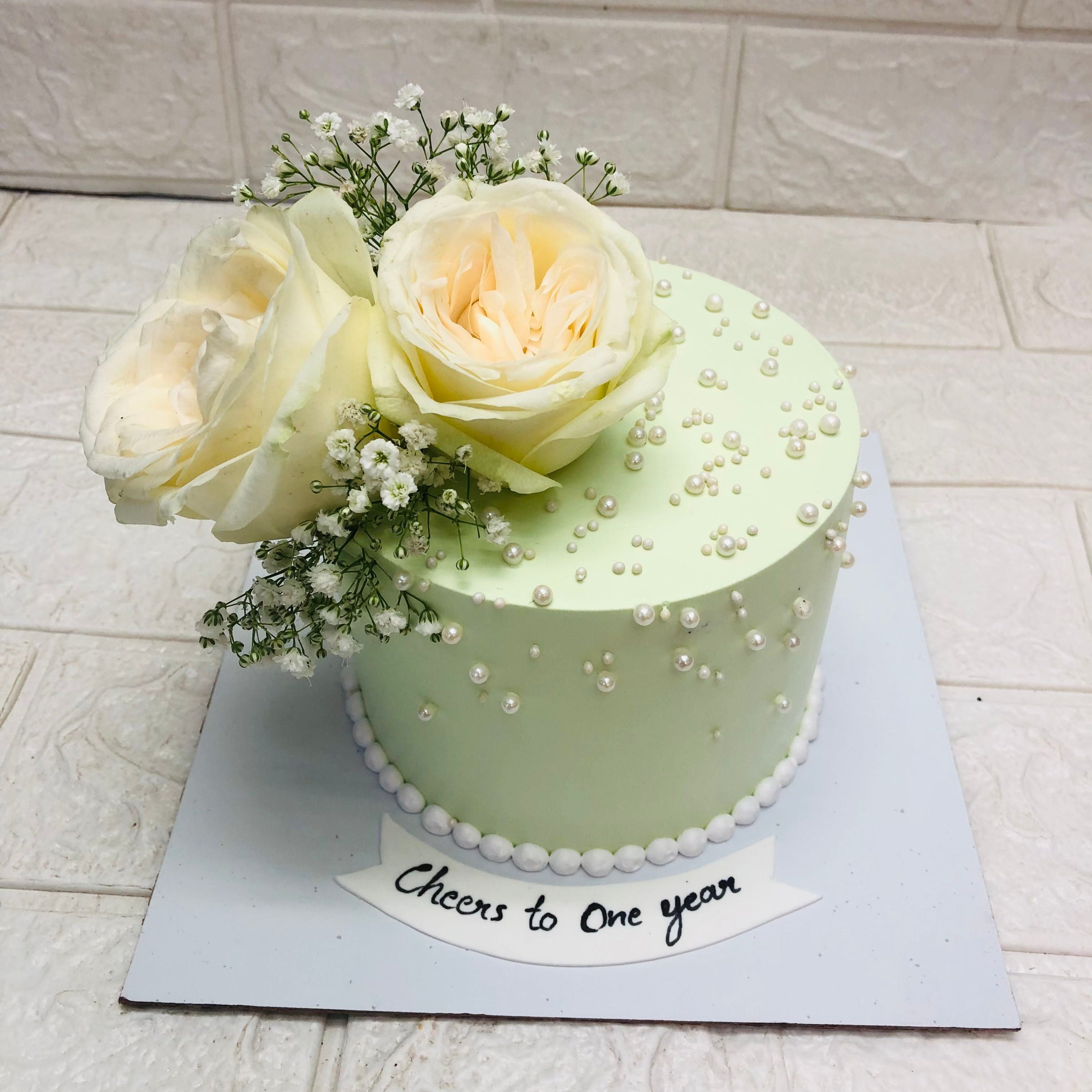 A petite green cake featuring beautiful white roses on top, creating a visually appealing and delightful dessert.