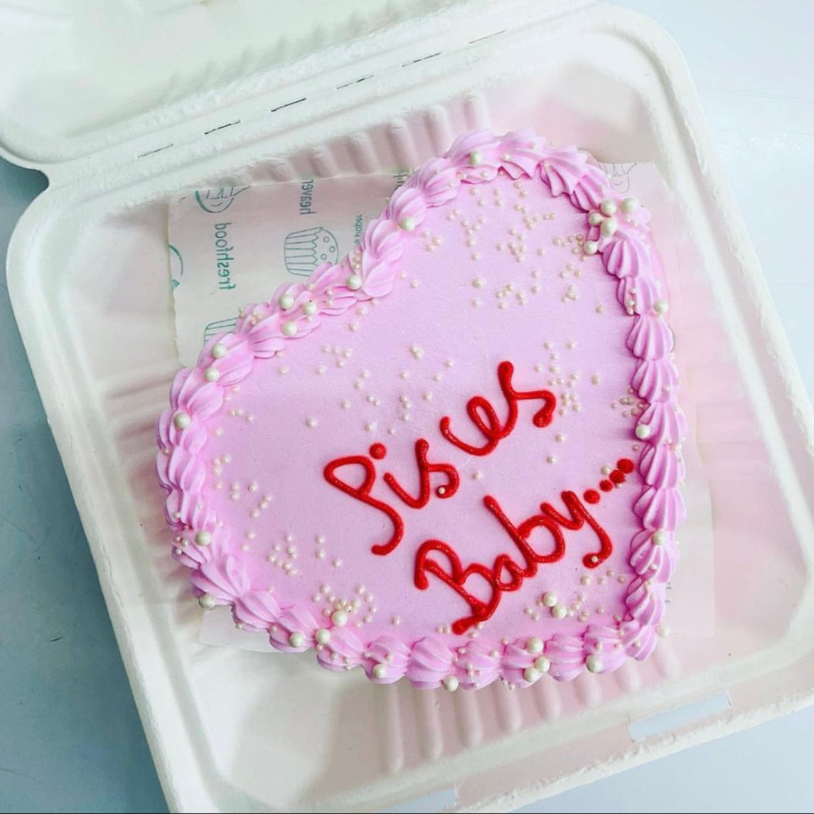 A delightful cake with pink icing, featuring the word "Pieces baby" elegantly written on top. Perfect for a baby shower celebration!